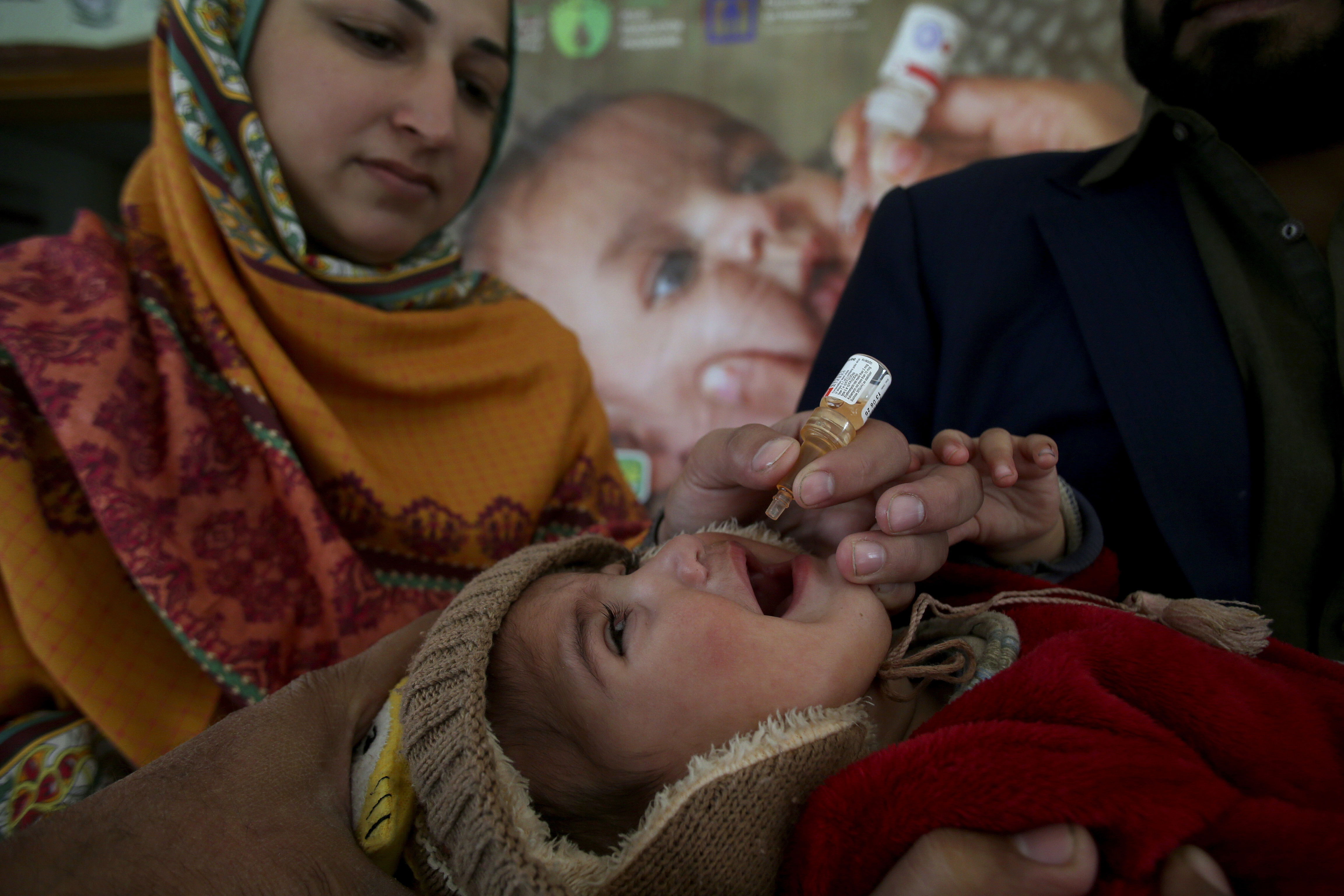 A health worker administers a polio vaccine to a child at a health center in Peshawar, Pakistan, Monday, Dec. 16, 2024. (AP Photo/Muhammad Sajjad)