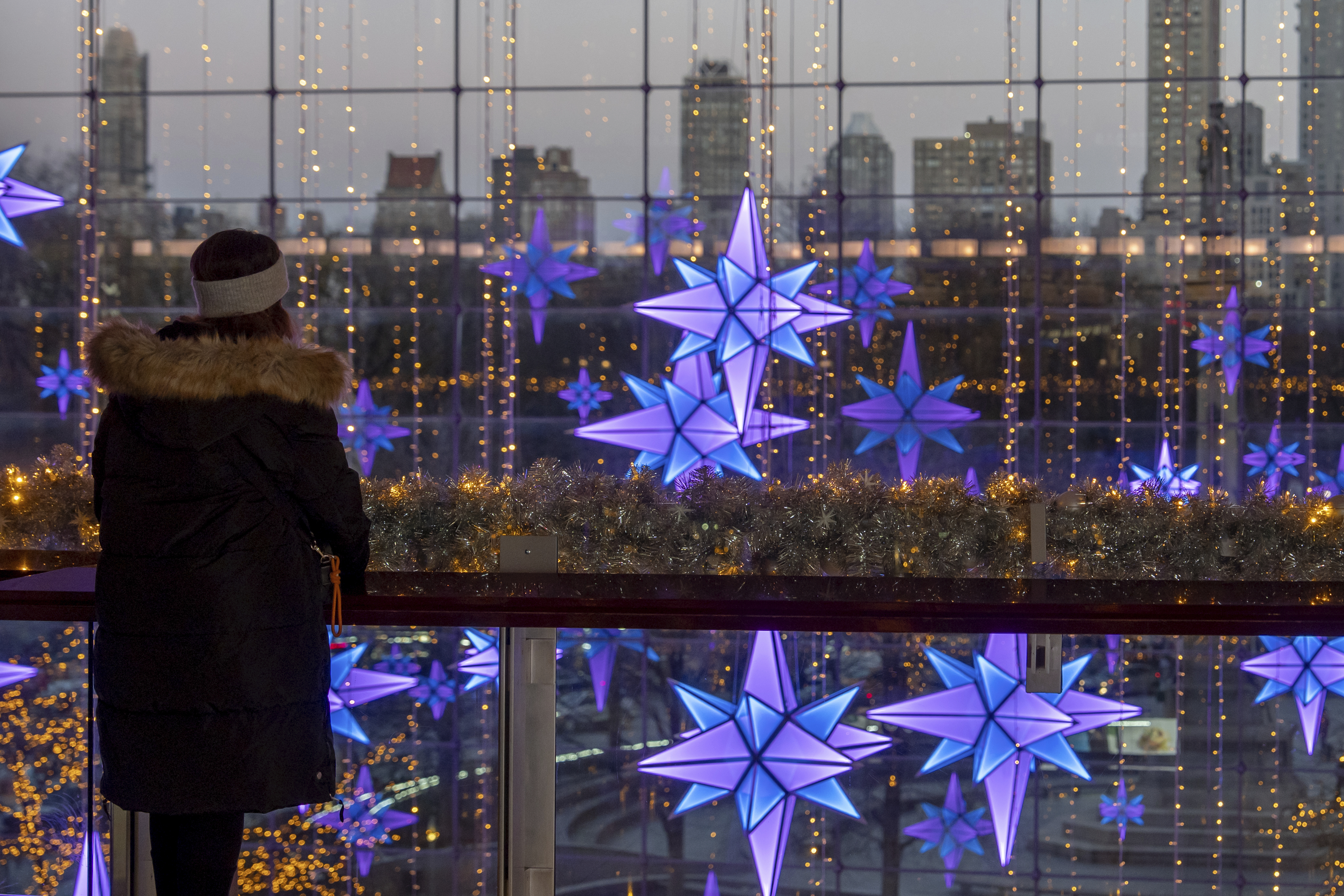 A person views lights in front of the New York skyline at The Shops at Columbus Circle, Thursday, Dec. 12, 2024, in New York. (AP Photo/Julia Demaree Nikhinson)