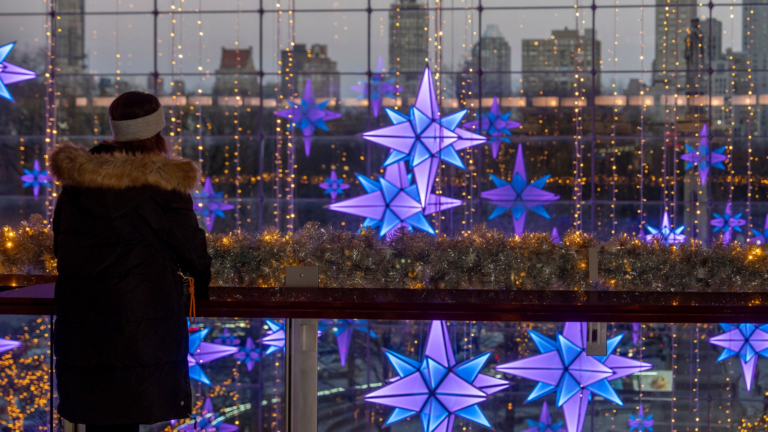 A person views lights in front of the New York skyline at The Shops at Columbus Circle, Thursday, Dec. 12, 2024, in New York. (AP Photo/Julia Demaree Nikhinson)