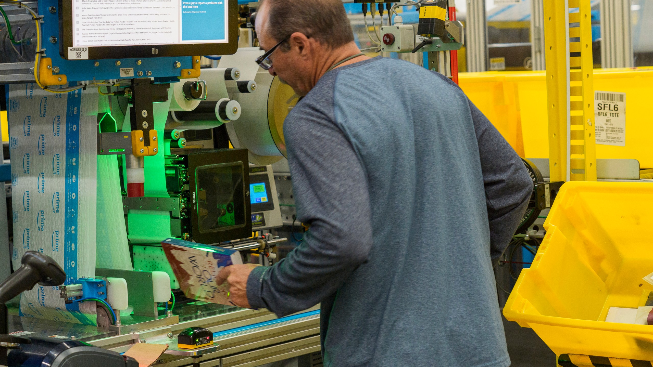 FILE - An employee uses an automated packaging machine to create a made-to-measure bag for a book at Amazon OXR1 fulfillment center in Oxnard, Calif., on Aug. 21, 2024. (AP Photo/Damian Dovarganes, File)