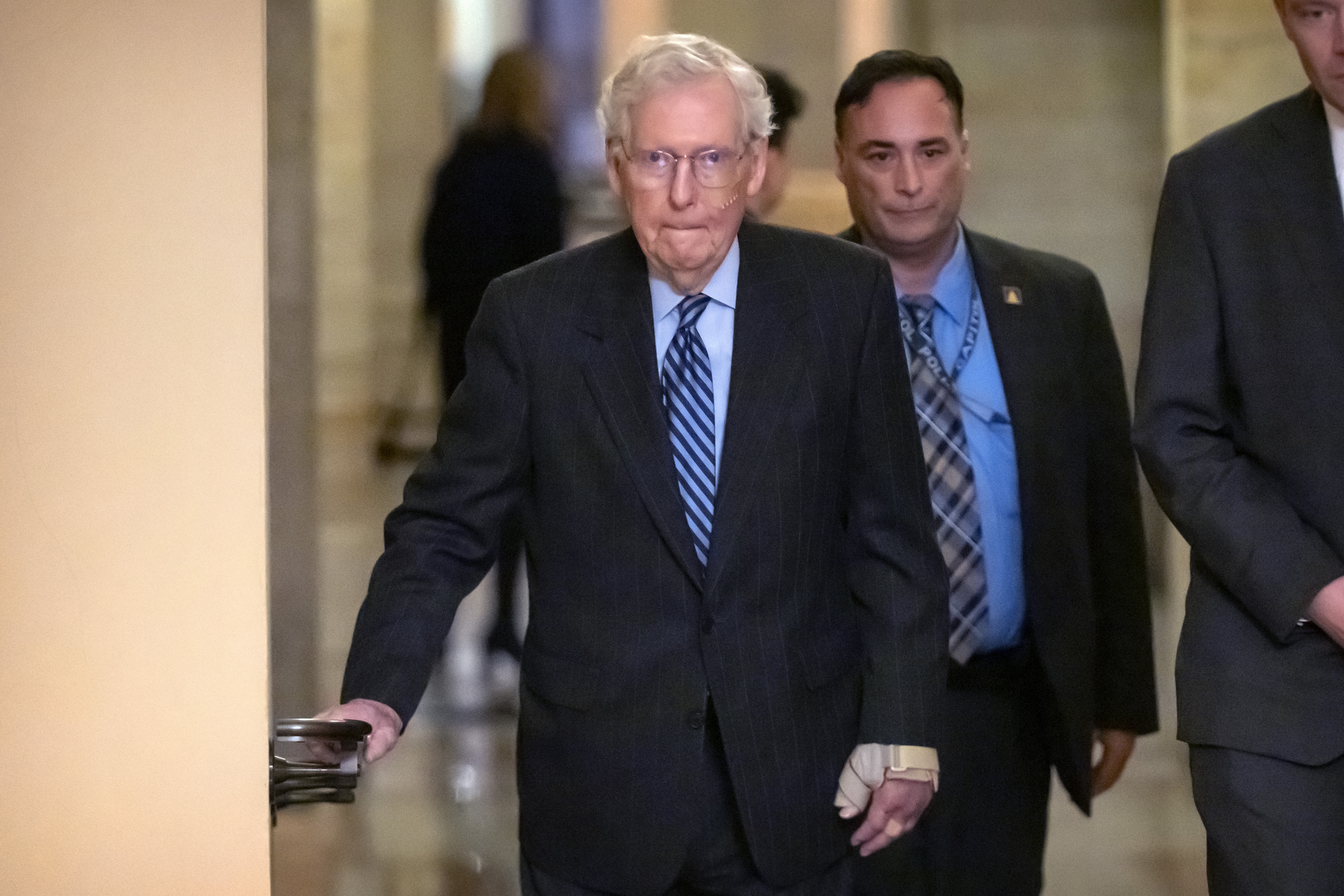 Senate Minority Leader Mitch McConnell of Ky., left, wears a bandage on his face and wrist as he walks to cast a vote on the Senate floor after falling during a luncheon on Capitol Hill, Tuesday, Dec. 10, 2024, in Washington. (AP Photo/Mark Schiefelbein)