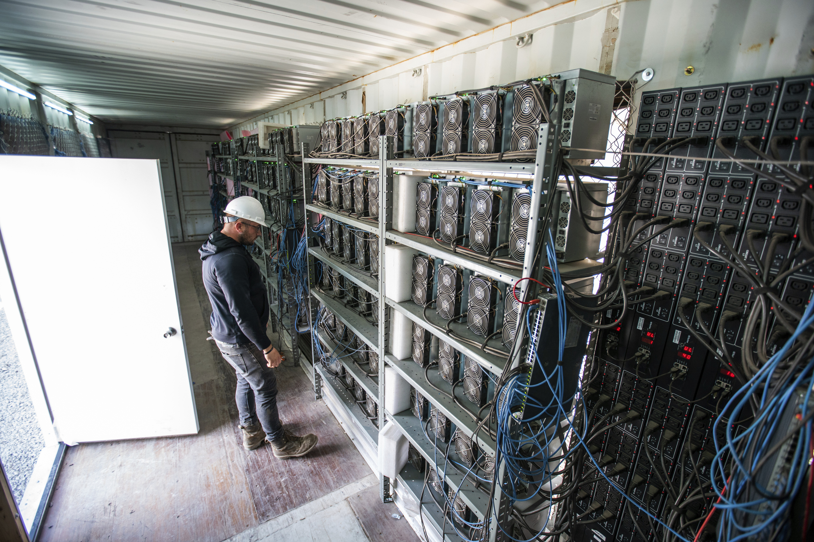 FILE - Chris Radwanski, data center supervisor, checks on Bitcoin mining machines in a shipping container behind the Scrubgrass Power plant in Russellton, Pa., July 23, 2021. (Andrew Rush/Pittsburgh Post-Gazette via AP, File)