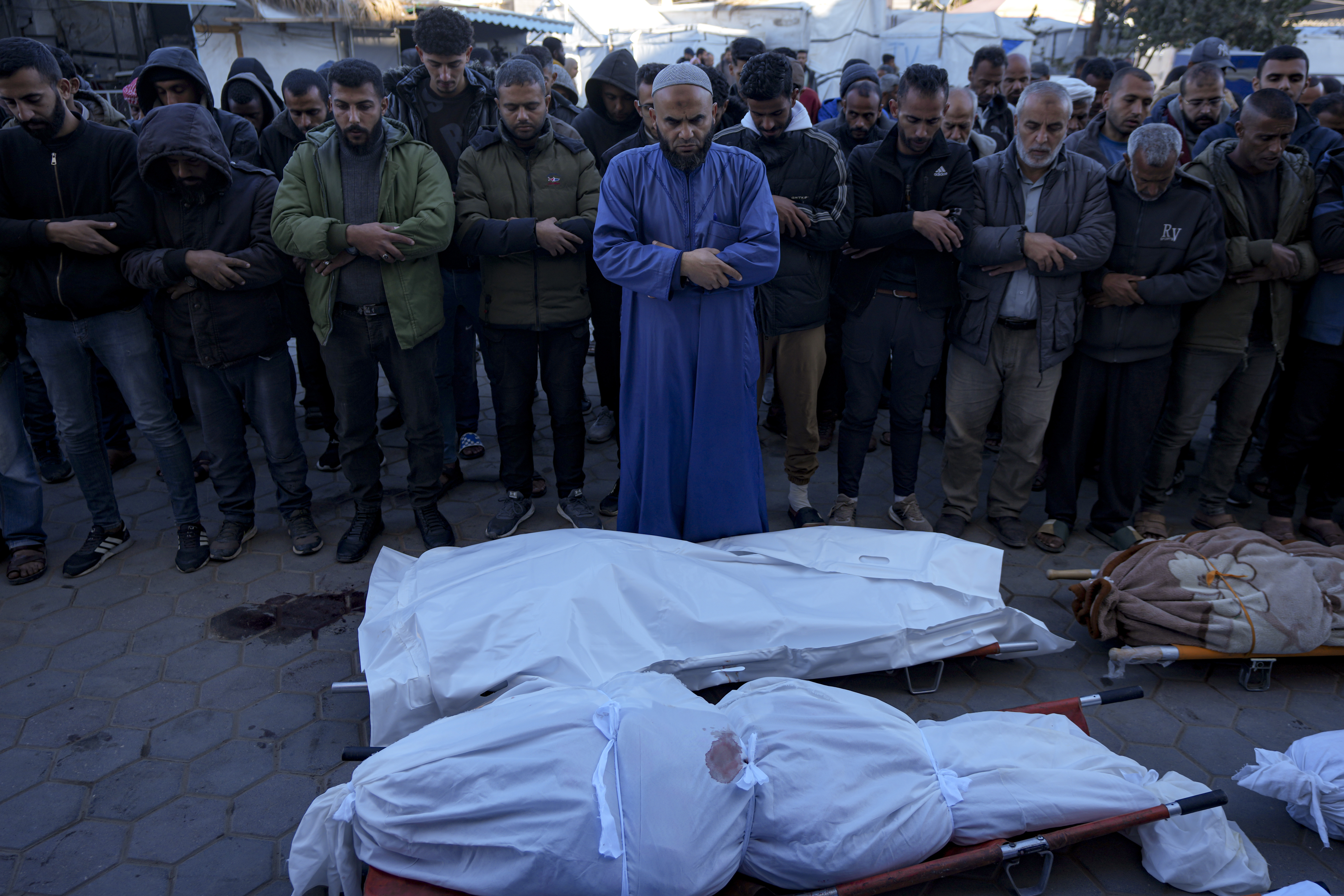 Palestinians pray next to the bodies of their relatives killed in the Israeli bombardment of the Gaza Strip, at a hospital in Deir al-Balah, Sunday, Dec. 15, 2024. (AP Photo/Abdel Kareem Hana)