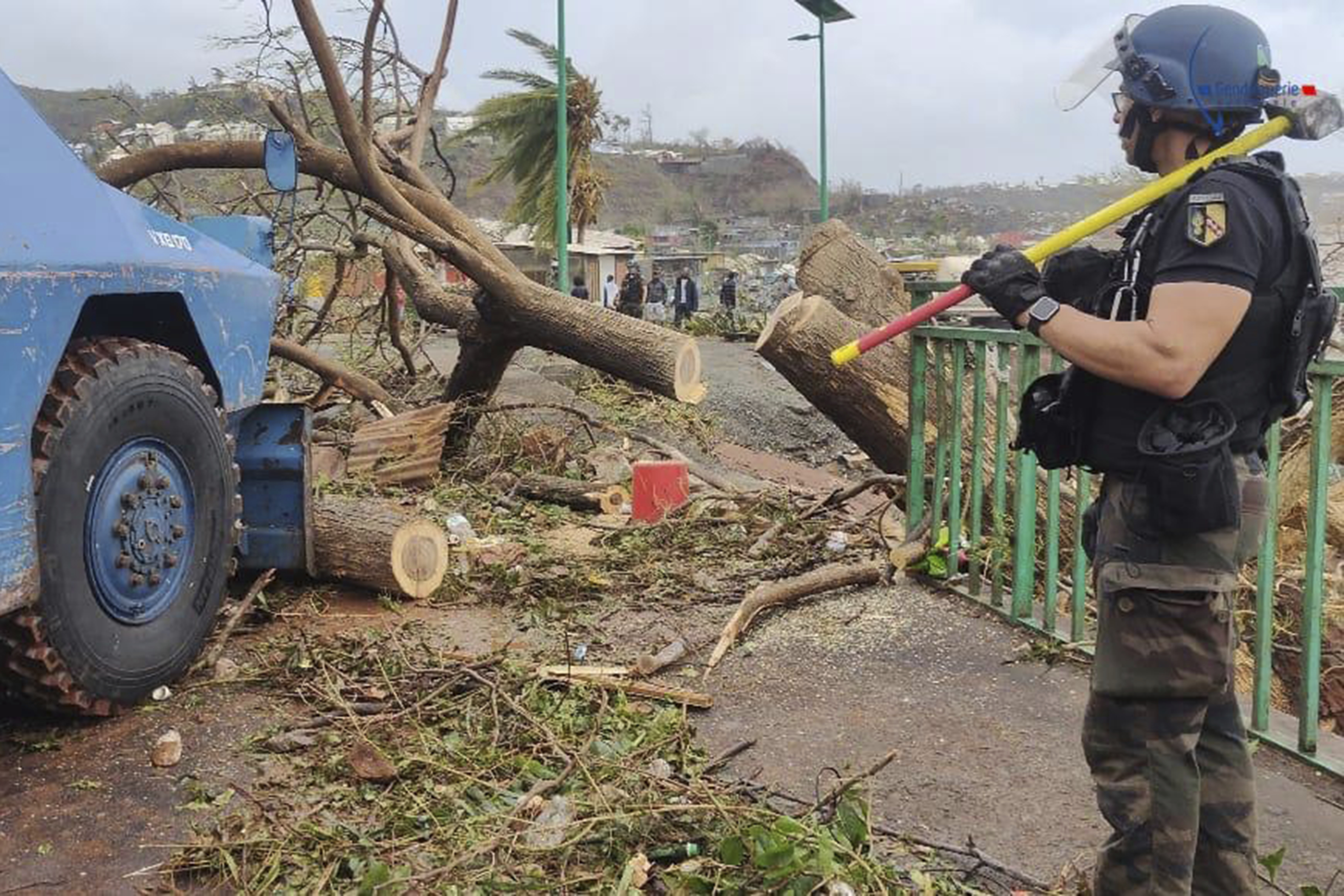 This photo provided on Monday Dec.16, 2024 by the Gendarmerie Nationale, shows a member of the Gendarmerie Nationale watching an armored vehicle clearing a road Sunday, Dec. 15, 2024 in Mayotte as France rushed rescue teams and supplies to its largely poor overseas department in the Indian Ocean that has suffered widespread destruction. (Gendarmerie Nationale via AP)