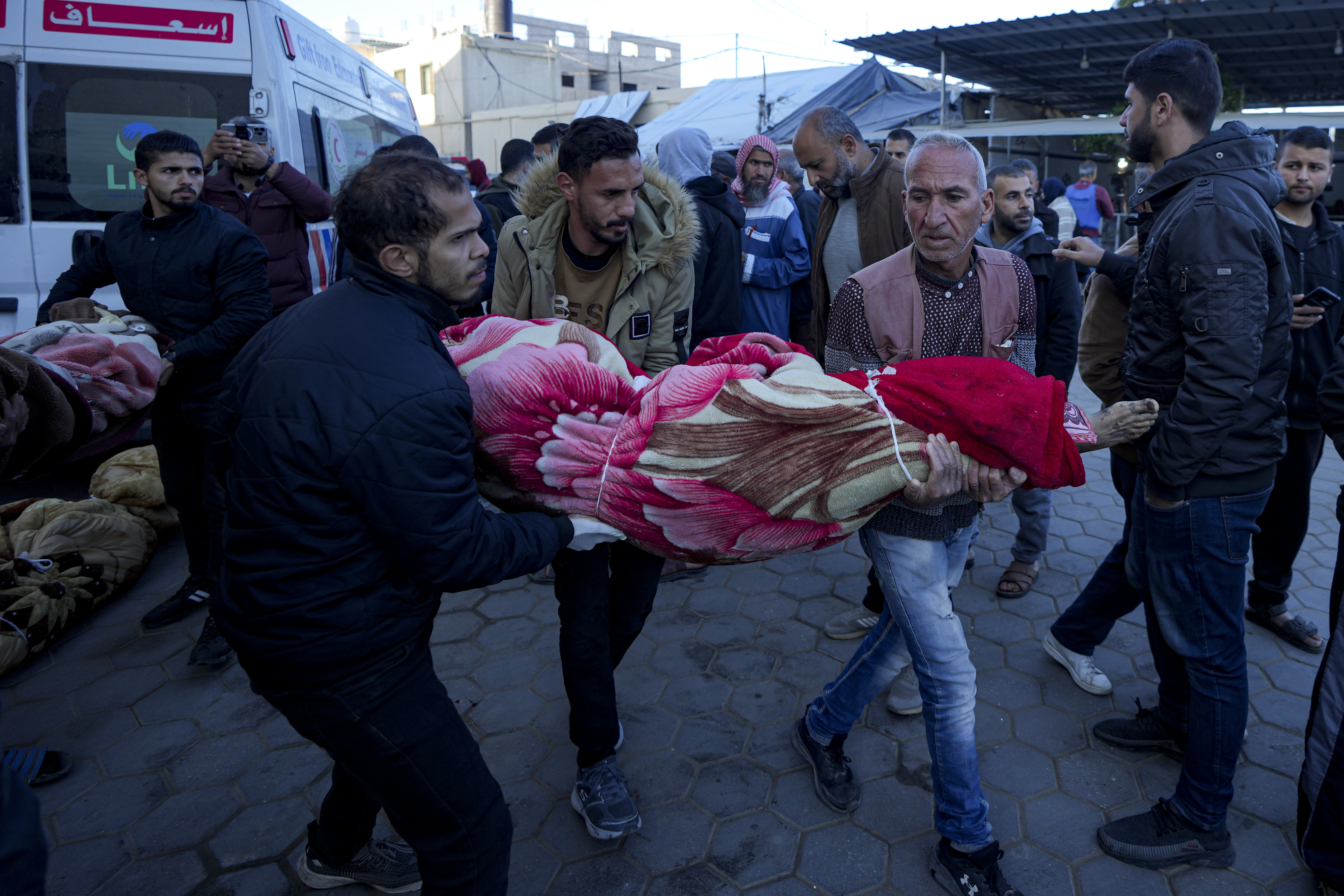 Palestinians carry the body of a relative killed in the Israeli bombardment of the Gaza Strip at a hospital in Deir al-Balah, Sunday, Dec. 15, 2024. (AP Photo/Abdel Kareem Hana)