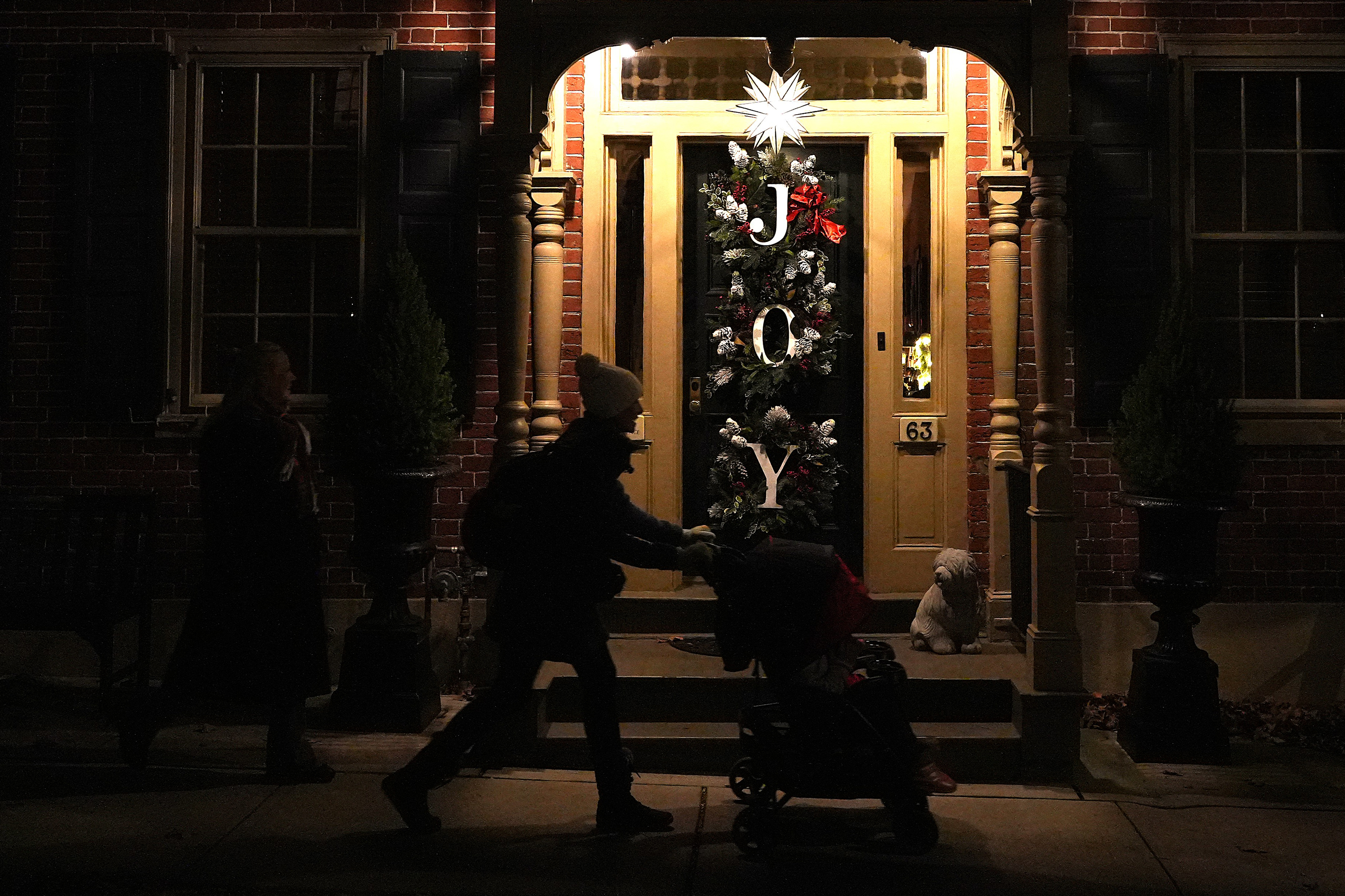 A woman pushes a stroller in front of a house decorated with a Moravian star and Christmas wreaths in Bethlehem, Pa., on Sunday, Dec. 1, 2024. (AP Photo/Luis Andres Henao)