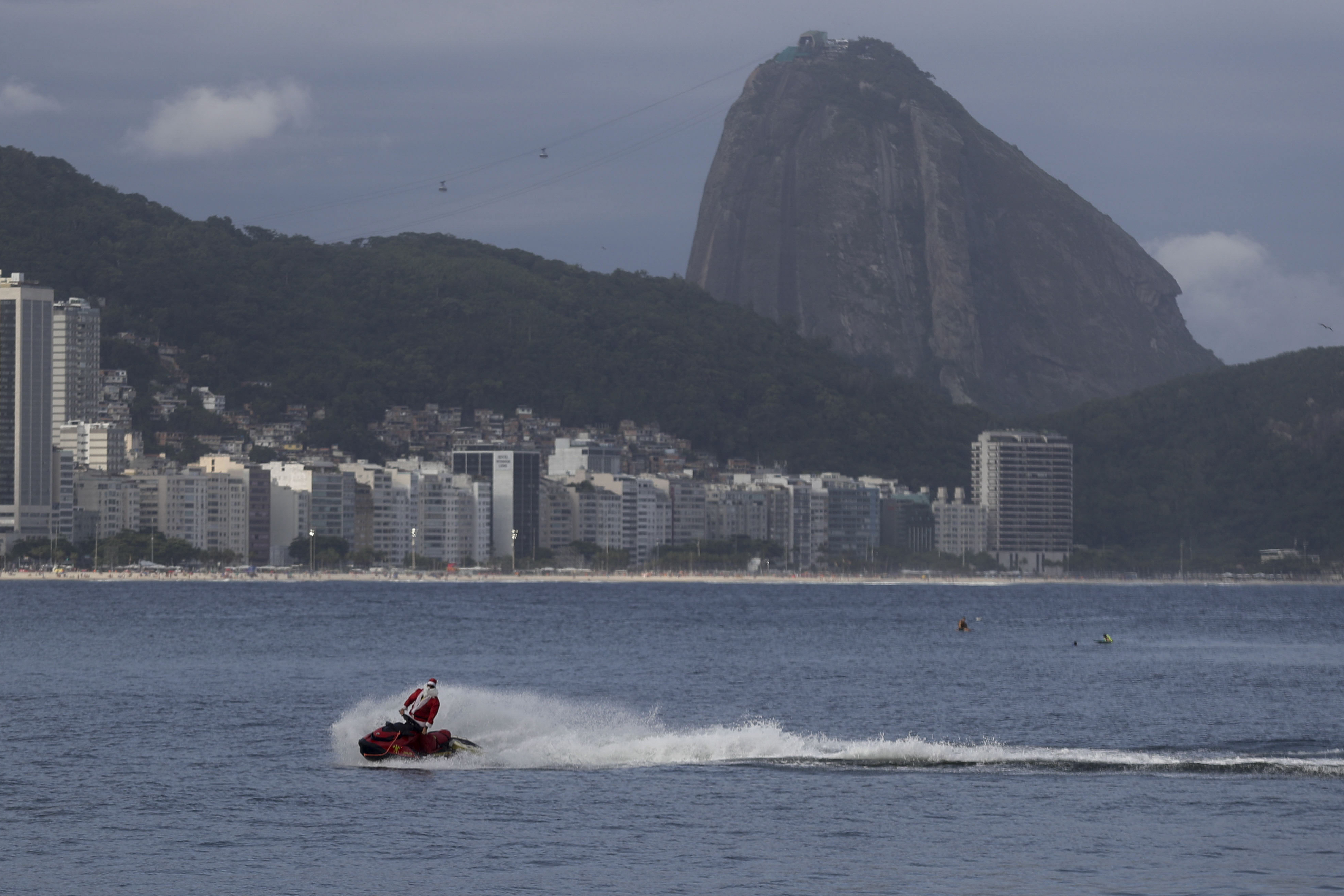 A firefighter dressed as Santa Claus drives a Jet Ski by Copacabana Beach in Rio de Janeiro, Tuesday, Dec. 17, 2024. (AP Photo/Bruna Prado)