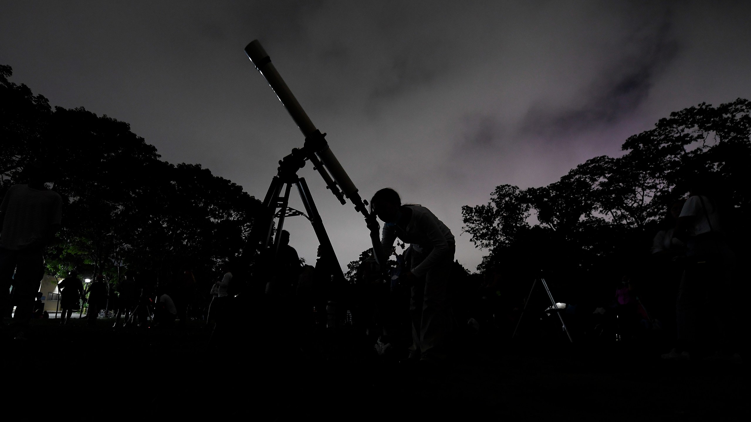 FILE - A girl looks through a telescope in Caracas, Venezuela, on Sunday, May 15, 2022. (AP Photo/Matias Delacroix, File)