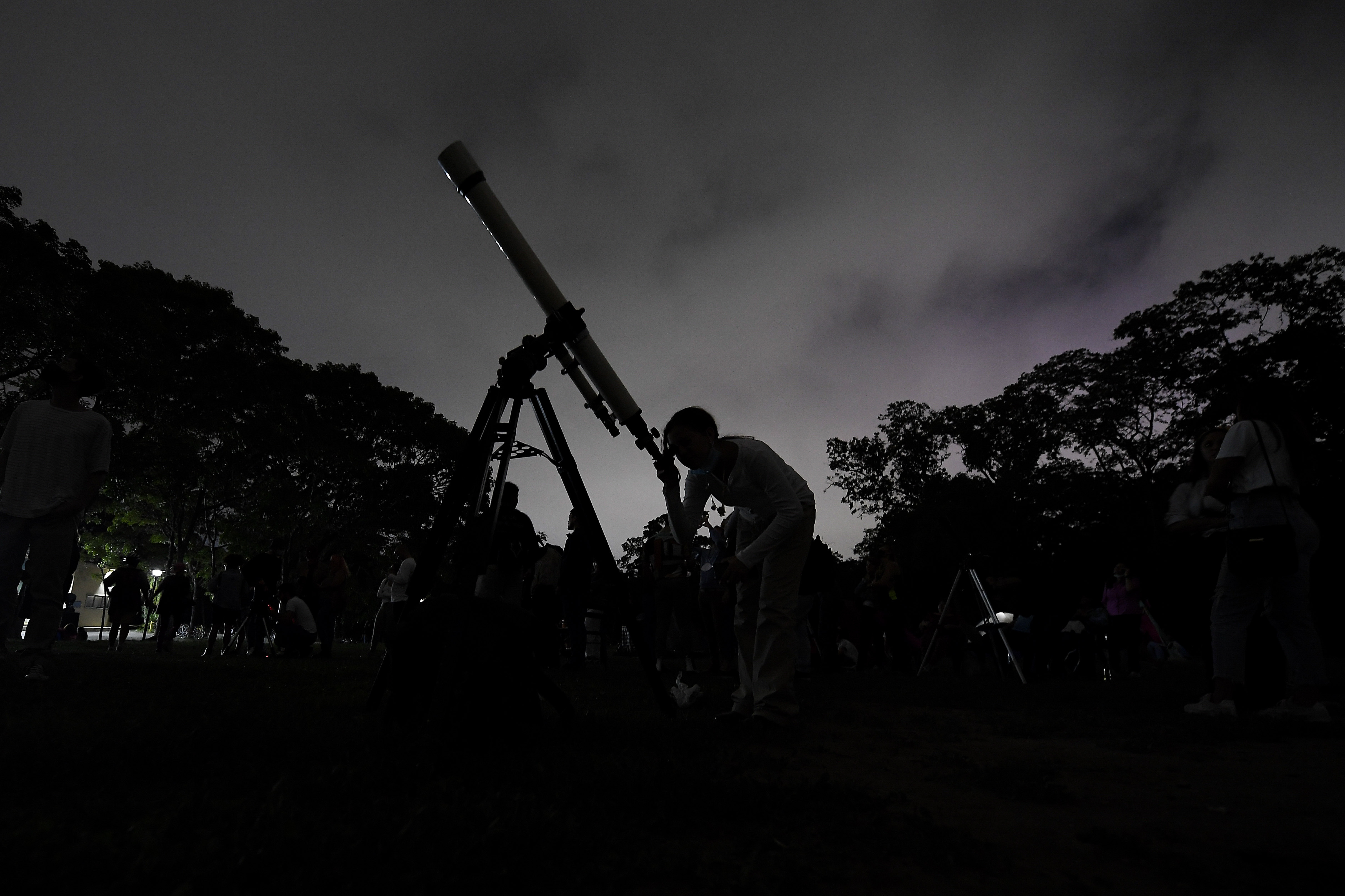 FILE - A girl looks through a telescope in Caracas, Venezuela, on Sunday, May 15, 2022. (AP Photo/Matias Delacroix, File)