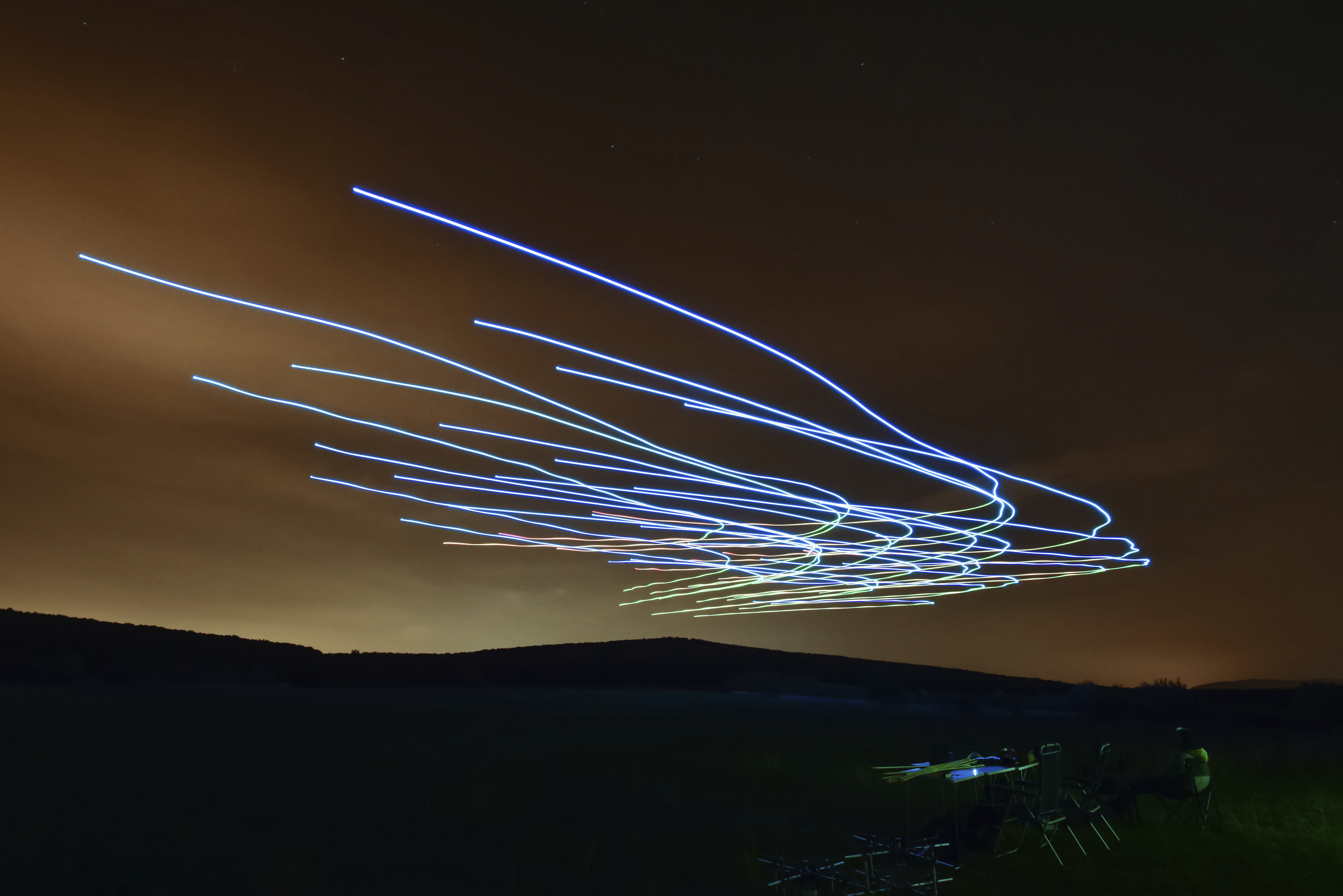 This handout photo taken with long exposure shows a researcher of the Eötvös Loránd University observing the flight of a flock of autonomous drones during an experiment near Budapest, Hungary, Thursday, Oct. 21, 2021. (AP Photo/HO/Eotvos Lorand University)