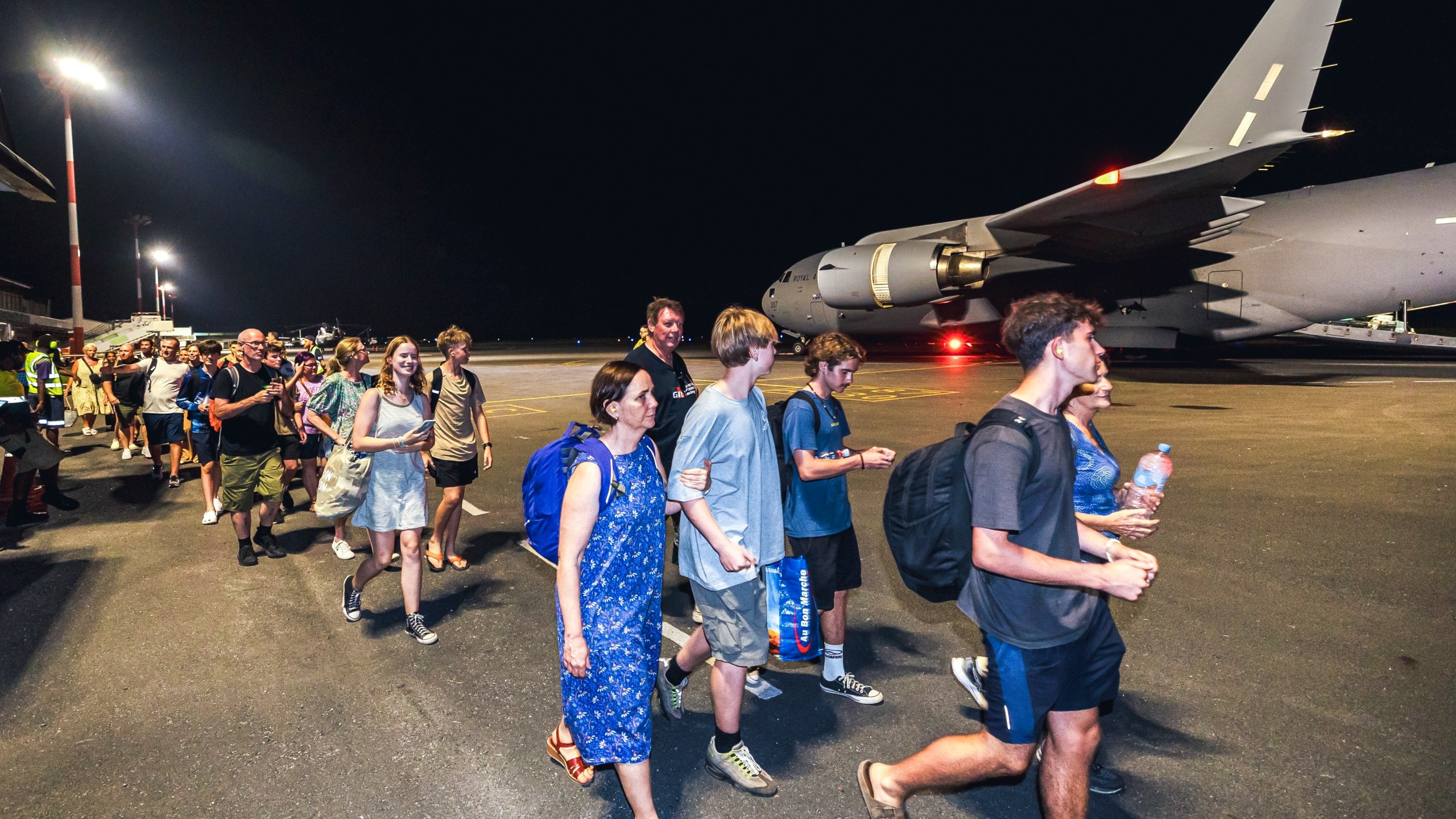 In this photo released by Australian Department of Defence, Australian citizens board a Royal Australian Air Force aircraft for a flight home from Bauerfield International Airport, Port Vila, Vanuatu, Wednesday, Dec. 18, 2024 following a powerful earthquake that struck just off the coast of Vanuatu in the South Pacific Ocean. (CPL Adam Abela/Australian Department of Defence via AP)