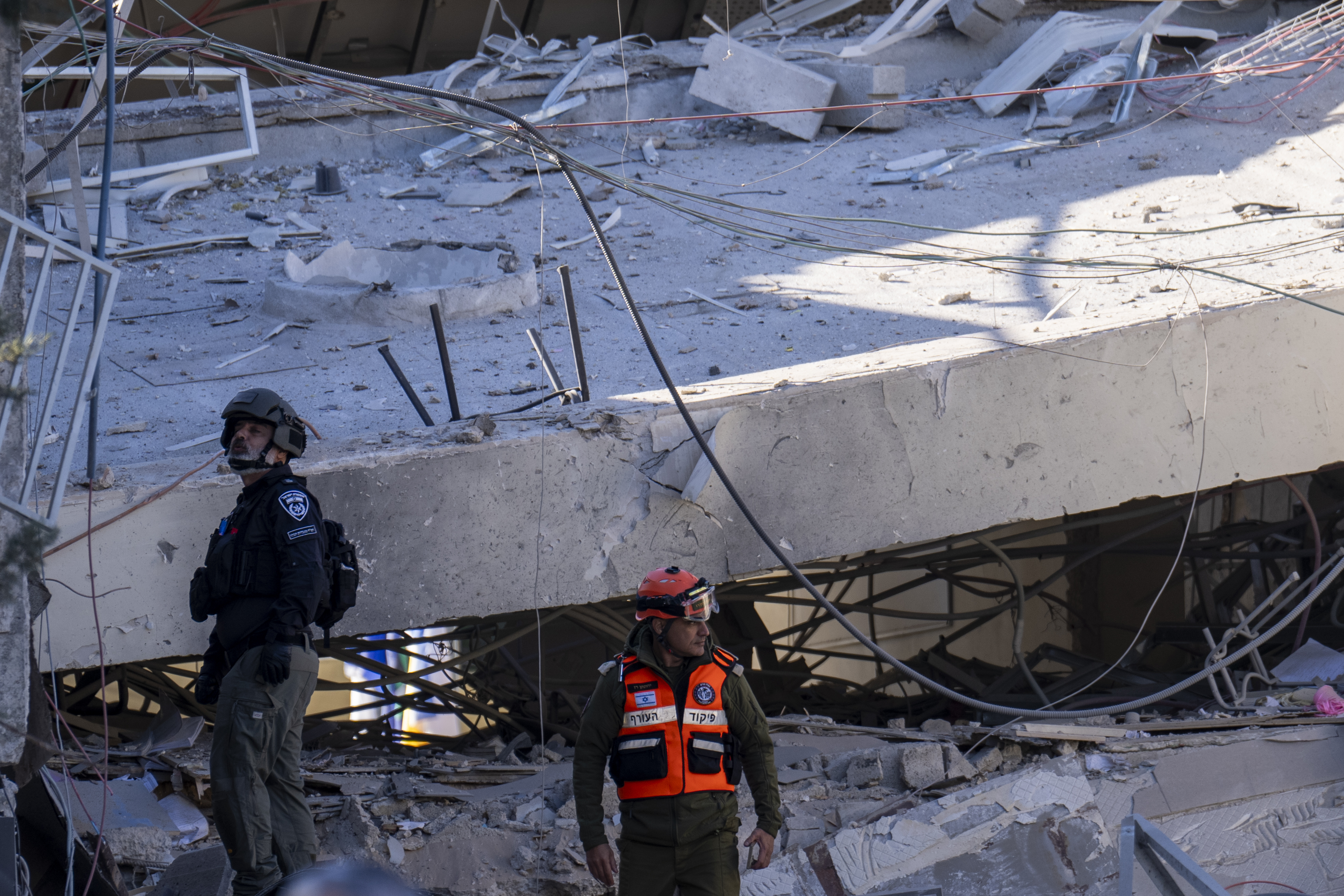 An officer from the home front command military unit and a policeman examine the damage after a large piece of shrapnel from Houthi missile collapsed a school building in Ramat Gan, a suburb of Tel Aviv, Israel, Thursday, Dec. 19, 2024. (AP Photo/Ariel Schalit)