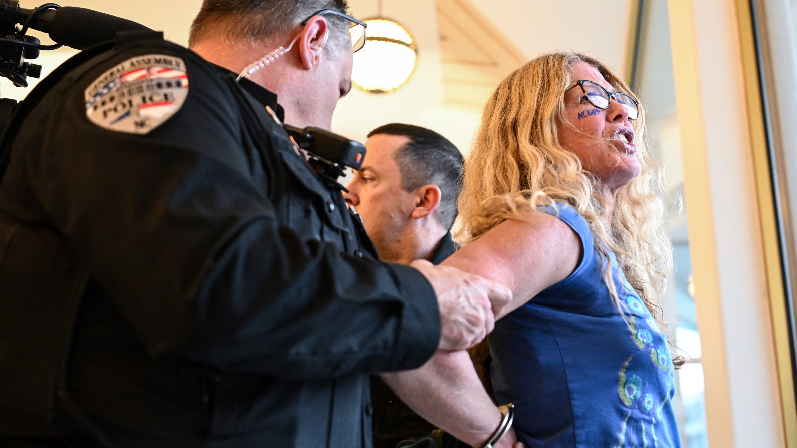 A demonstrator is placed under arrest after the Republican-dominated North Carolina House convened completed the override of Gov. Cooper's veto, Wednesday, Dec. 11, 2024, in Raleigh, N.C. (AP Photo/Matt Kelley)