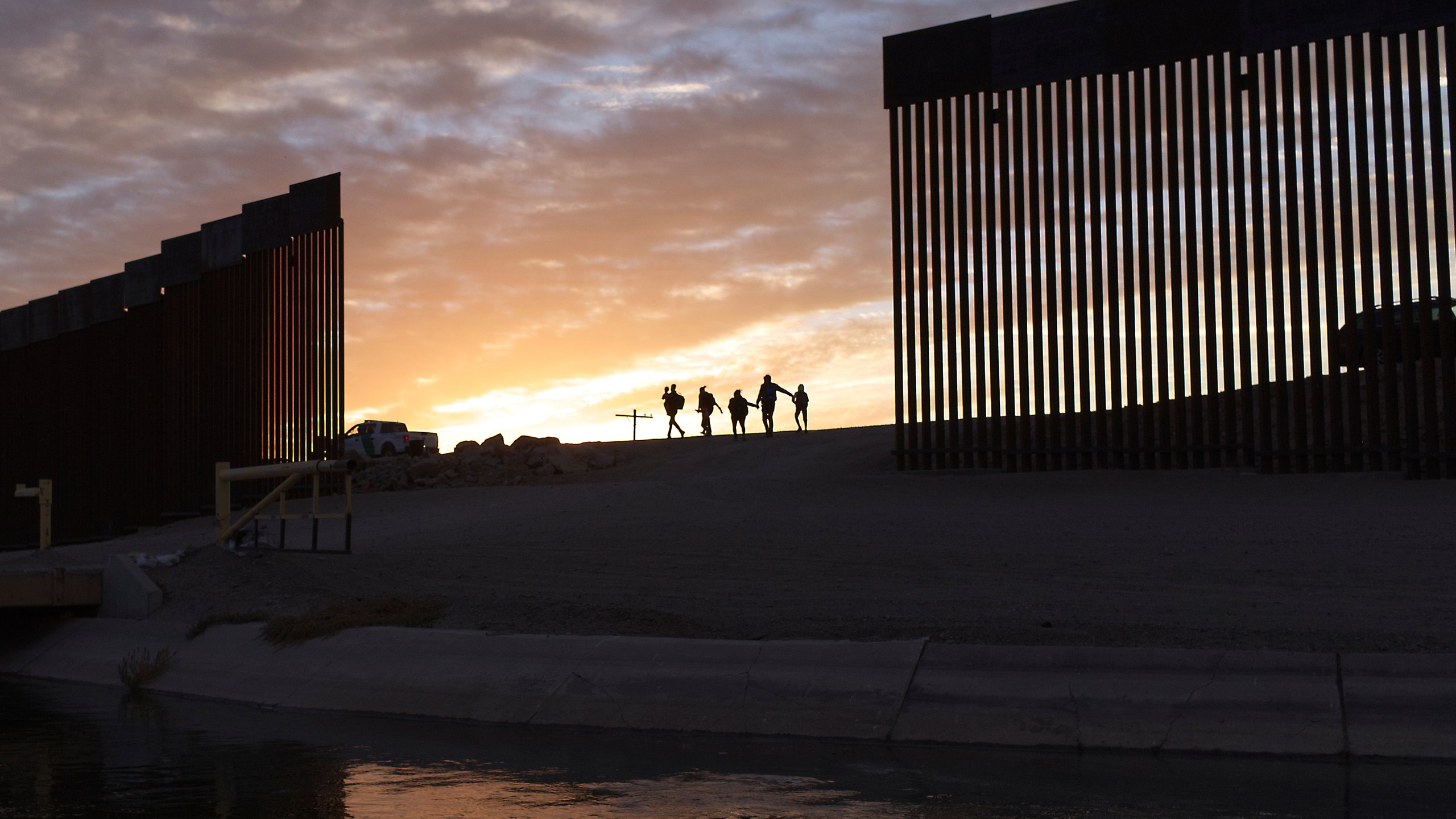 FILE - A pair of migrant families from Brazil pass through a gap in the border wall to reach the United States after crossing from Mexico in Yuma, Ariz., June 10, 2021, to seek asylum. (AP Photo/Eugene Garcia, File)