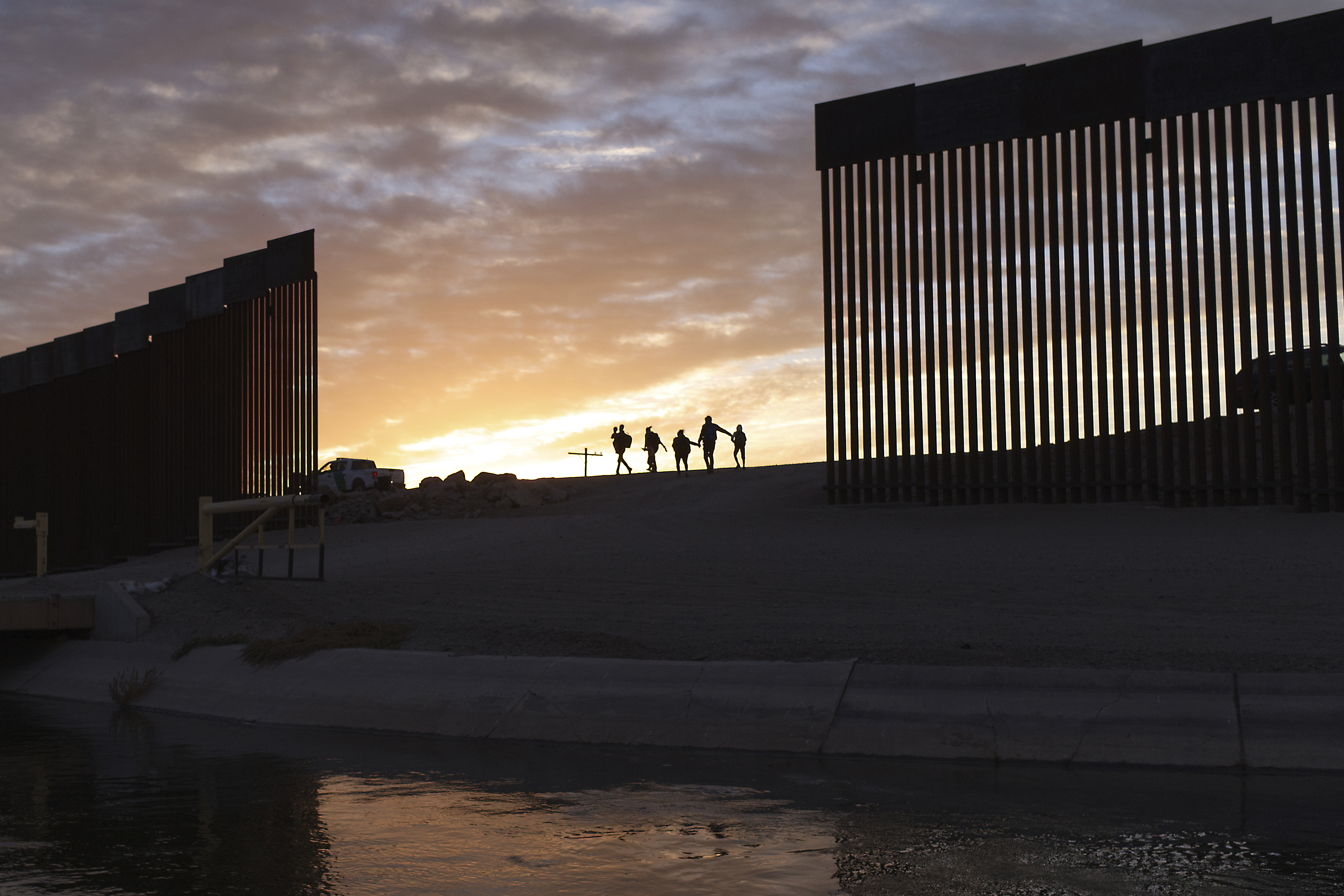 FILE - A pair of migrant families from Brazil pass through a gap in the border wall to reach the United States after crossing from Mexico in Yuma, Ariz., June 10, 2021, to seek asylum. (AP Photo/Eugene Garcia, File)