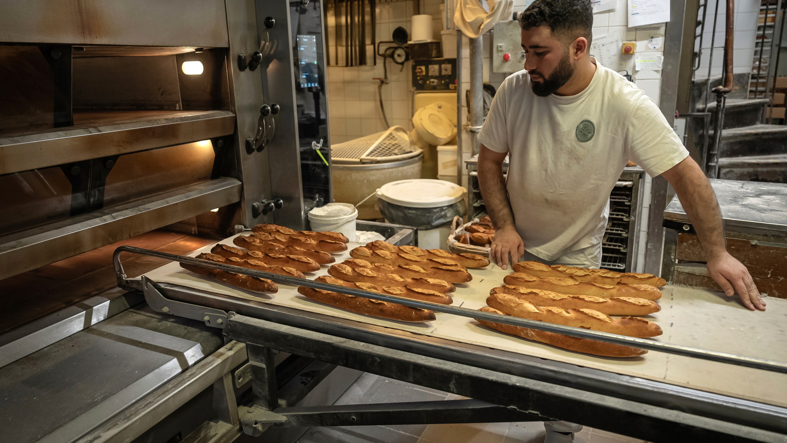 An employee removes bread for the oven in a bakery in Paris, Monday, Dec. 16, 2024 as butter has shot up in price across Europe in recent months, adding more pain to consumers this holiday season after years of inflation in the wake of the COVID-19 pandemic and war in Ukraine.(AP Photo/Aurelien Morissard)