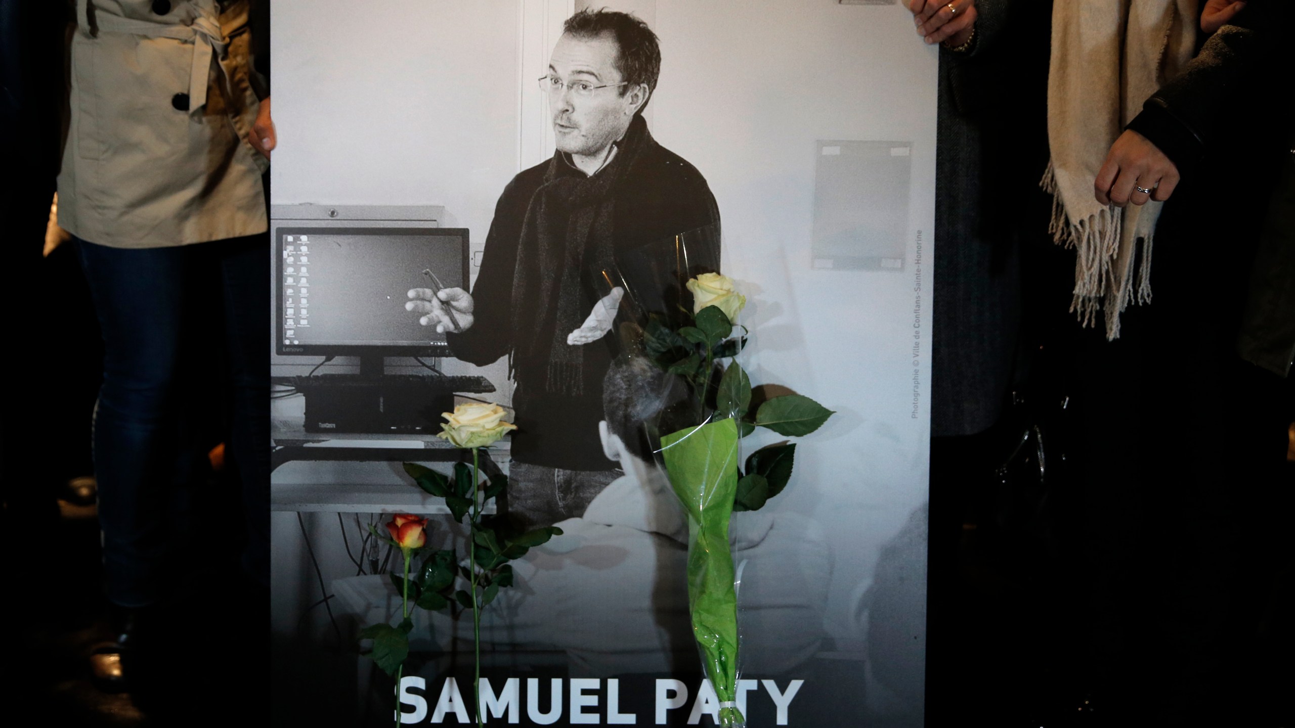 FILE - People hold a photo of the history teacher Samuel Paty , who was beheaded last week, during a memorial march in homage to him, Tuesday, Oct.20, 2020 in Conflans-Sainte-Honorine, northwest of Paris. (AP Photo/Lewis Joly, File)