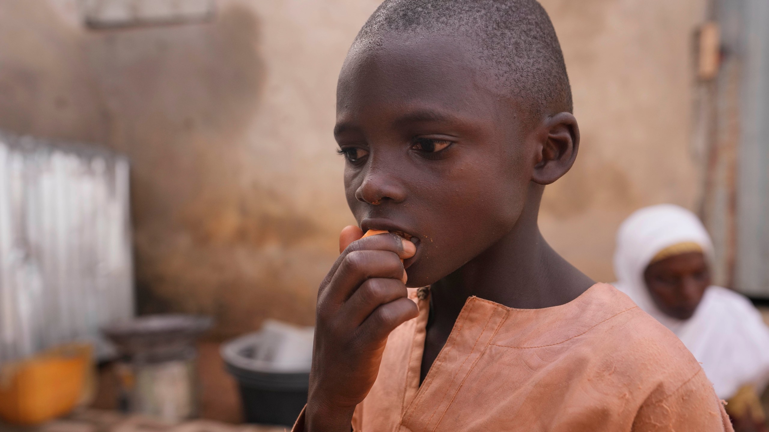 FILE - Hauwa Bwami's grandson Suleiman eats an orange-fleshed sweet potato, harvest from a farm inside their compound in Kaltungo Poshereng Nigeria, Sunday, June 2, 2024. (AP Photo/Sunday Alamba, File)