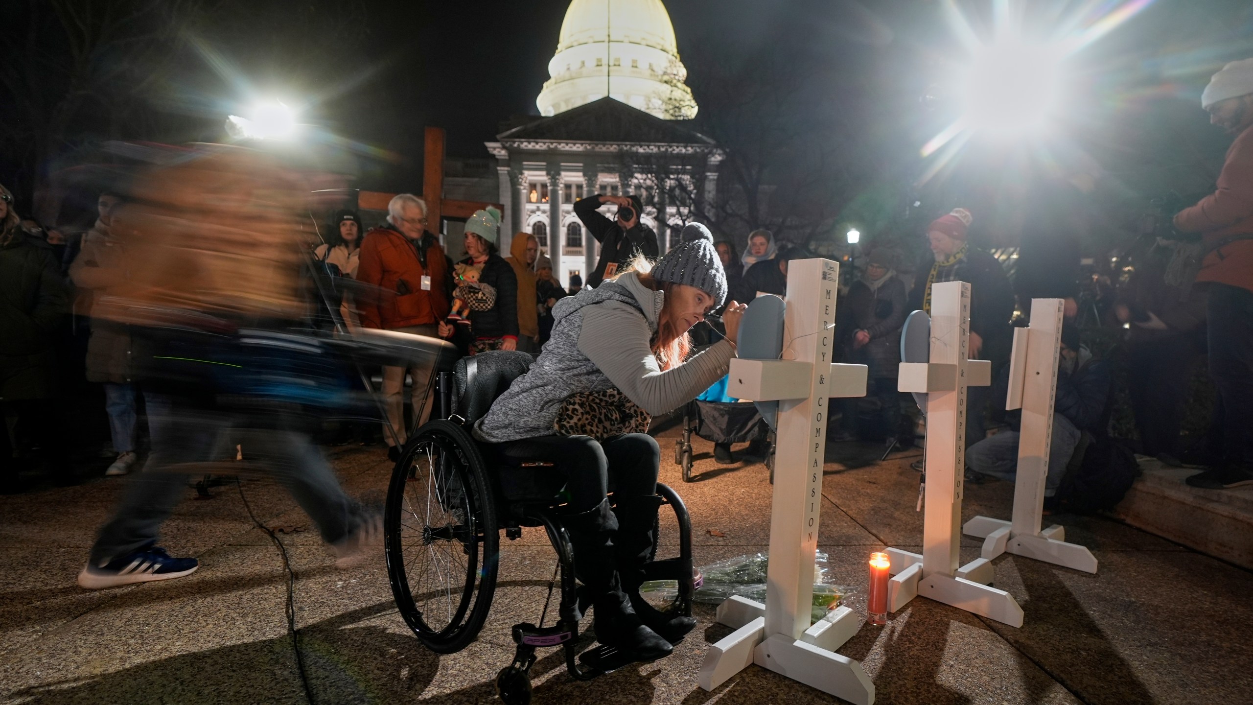 A supporter signs a cross during a candlelight vigil Tuesday, Dec. 17, 2024, outside the Wisconsin Capitol in Madison, Wis., following a shooting at the Abundant Life Christian School on Monday, Dec. 16. (AP Photo/Morry Gash)