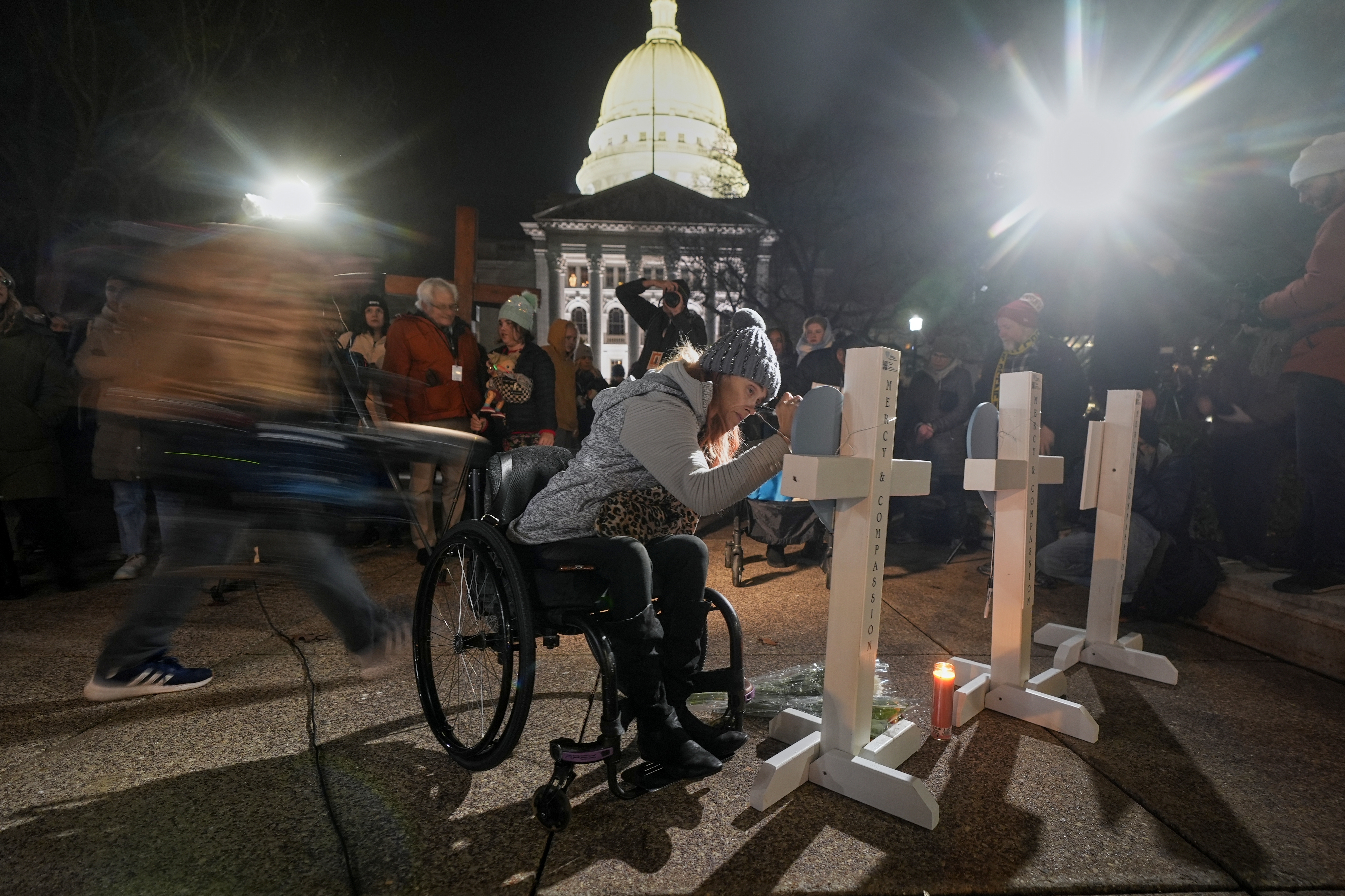 A supporter signs a cross during a candlelight vigil Tuesday, Dec. 17, 2024, outside the Wisconsin Capitol in Madison, Wis., following a shooting at the Abundant Life Christian School on Monday, Dec. 16. (AP Photo/Morry Gash)