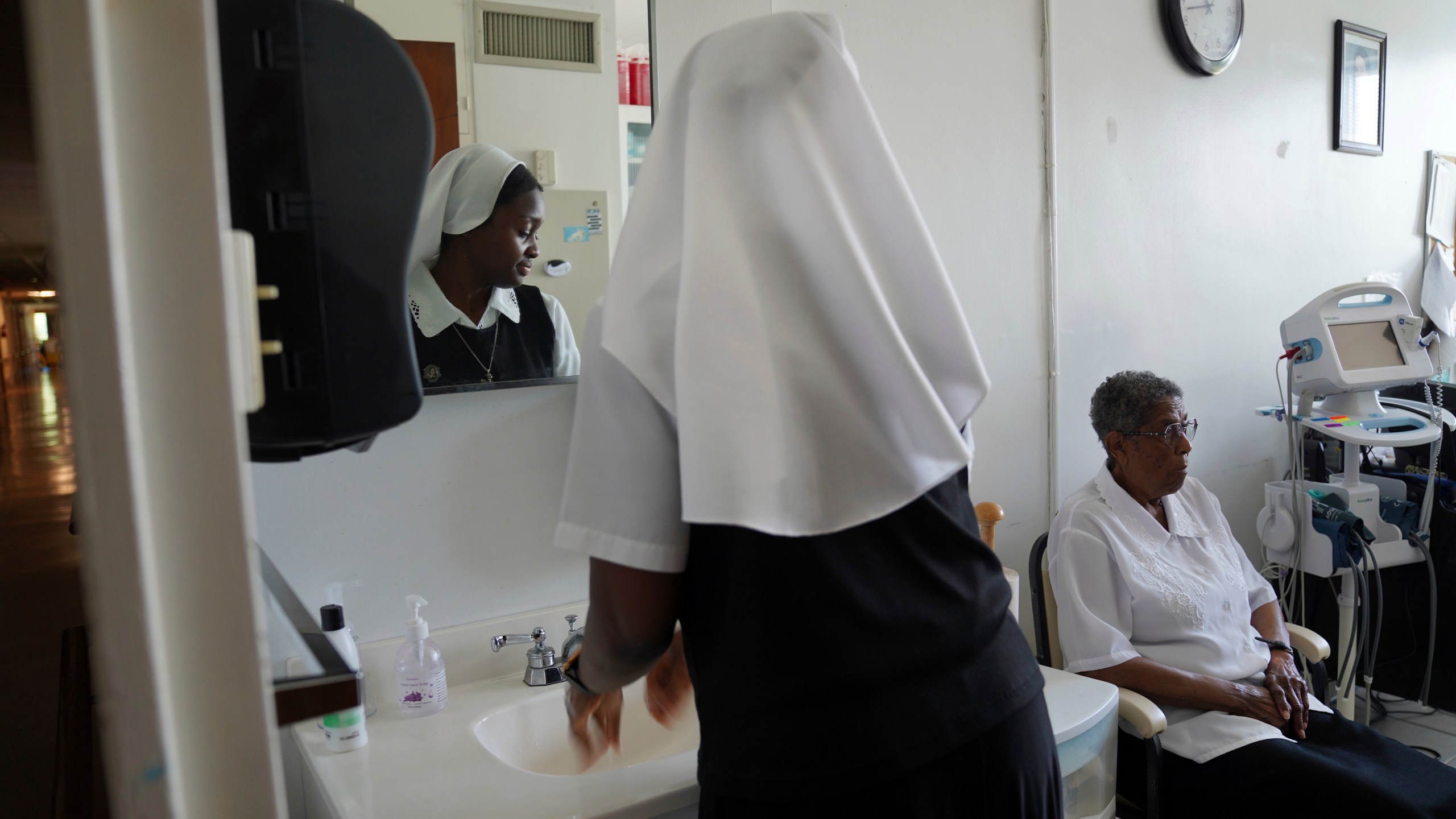 Sister Seyram Mary Adzokpa of the Sisters of the Holy Family cares for Sr. Clara Mae Jackson at the motherhouse in New Orleans, Tuesday, June 25, 2024. (AP Photo/Jessie Wardarski)