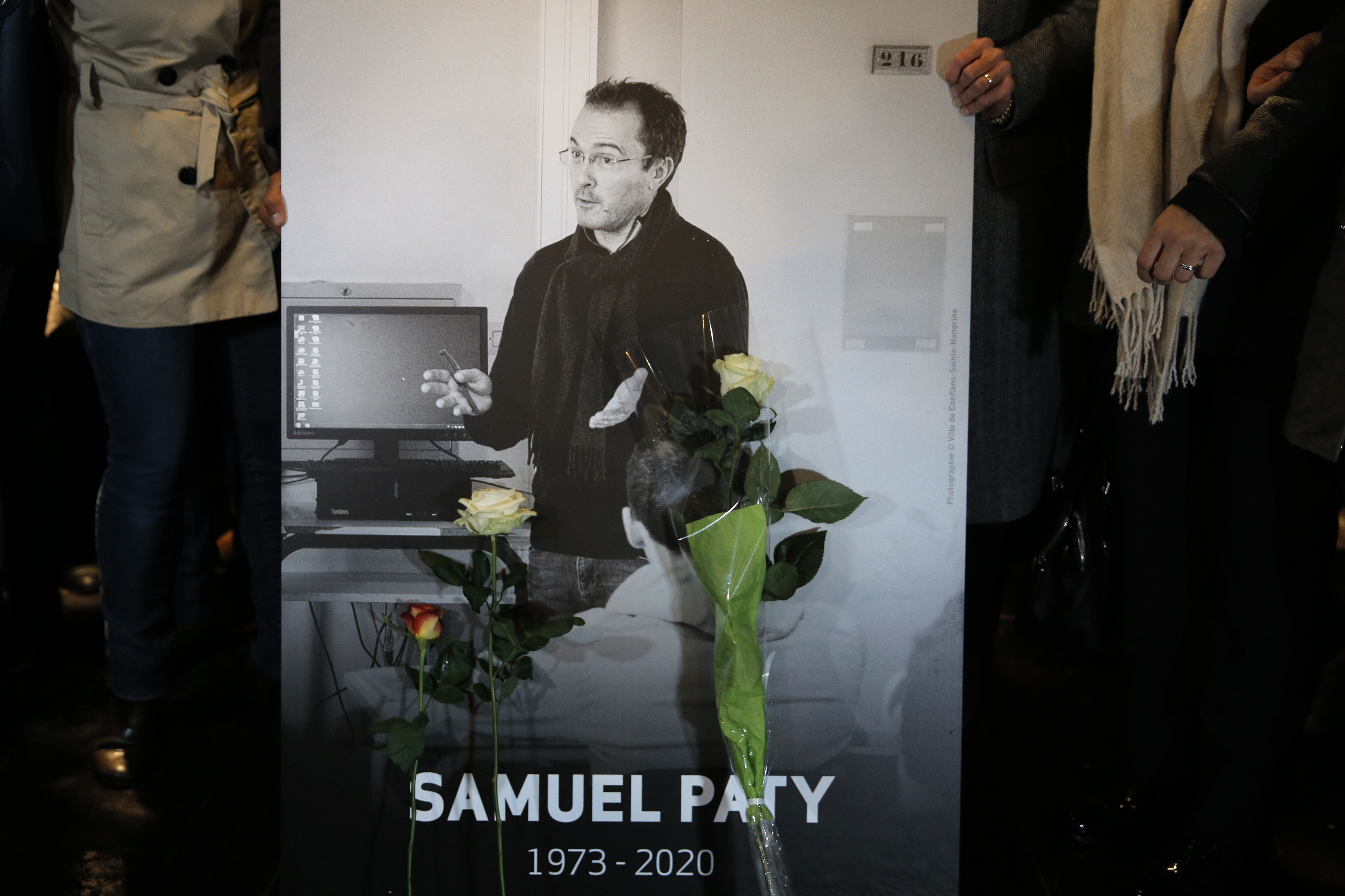 FILE - People hold a photo of the history teacher Samuel Paty , who was beheaded last week, during a memorial march in homage to him, Tuesday, Oct.20, 2020 in Conflans-Sainte-Honorine, northwest of Paris. (AP Photo/Lewis Joly, File)