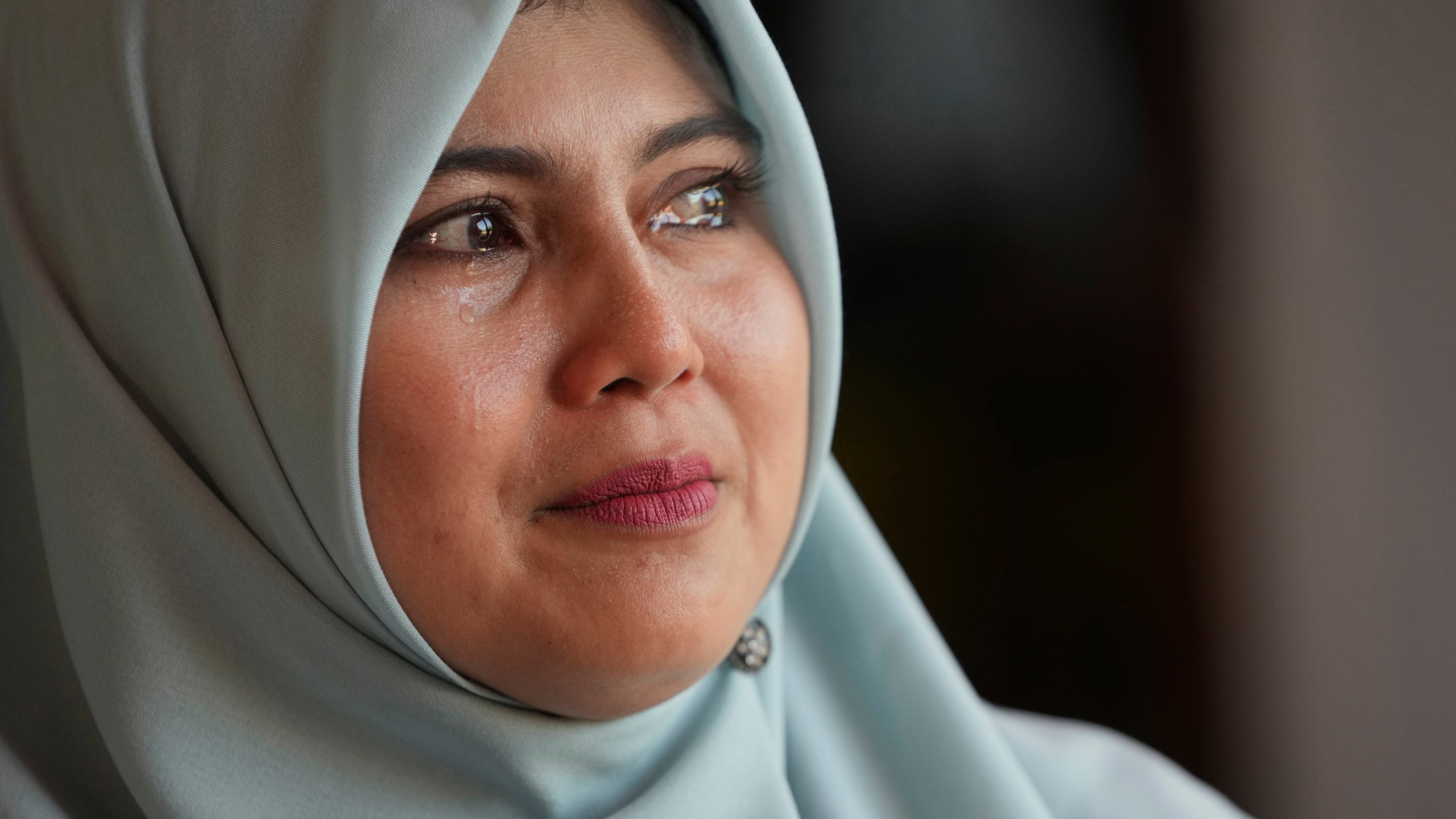 Tears well up in the eyes of Tria Asnani, a 38-year-old high school teacher teacher who is also a tsunami survivor, as he speaks with The Associated Press during an interview in Banda Aceh, Indonesia, Thursday, Dec. 12, 2024. (AP Photo/Achmad Ibrahim)