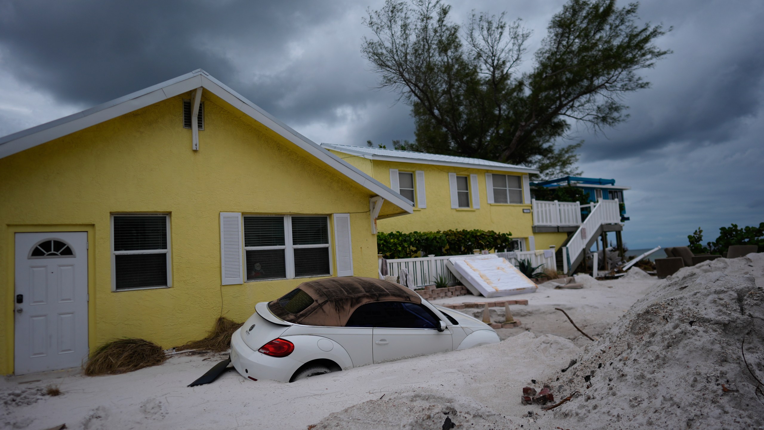 FILE - As Hurricane Milton approaches, a car sits half-buried in sand in Bradenton Beach, Fla., in the aftermath of Hurricane Helene, Oct. 8, 2024. (AP Photo/Rebecca Blackwell, File)