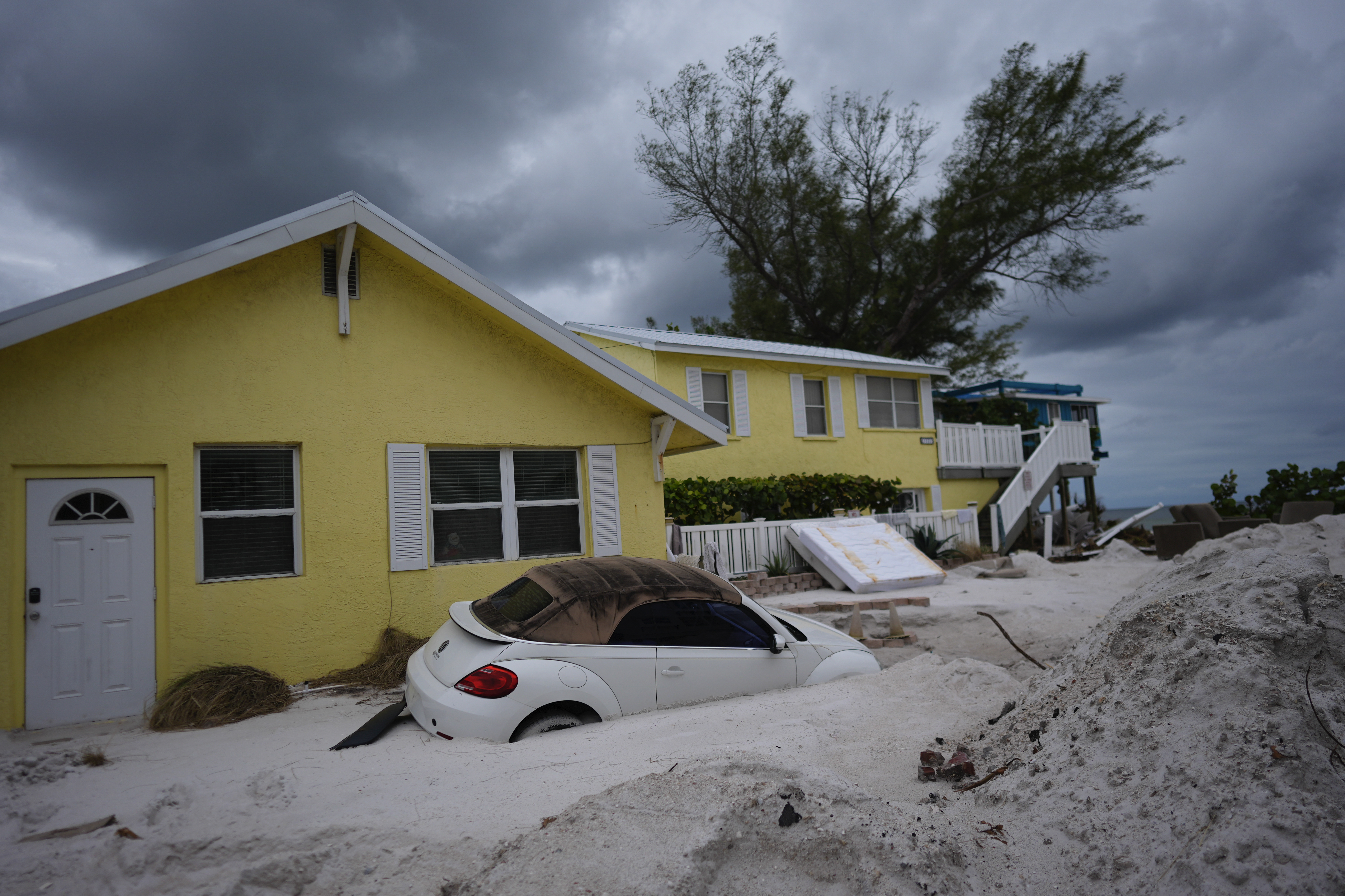 FILE - As Hurricane Milton approaches, a car sits half-buried in sand in Bradenton Beach, Fla., in the aftermath of Hurricane Helene, Oct. 8, 2024. (AP Photo/Rebecca Blackwell, File)