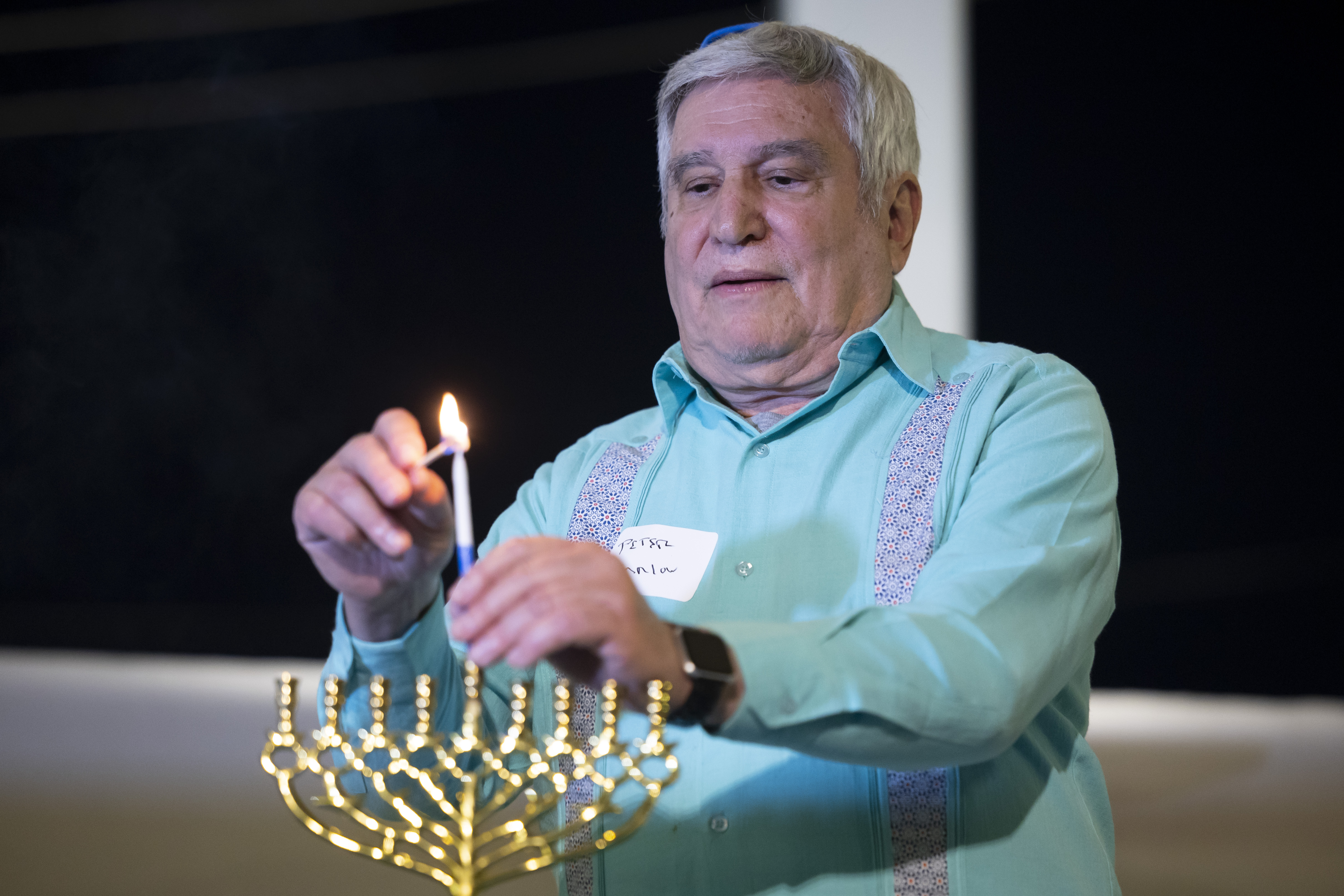 Rabbi Peter Tarlow lights a candle on a menorah during a Chicanukah event at Holocaust Museum Houston on Thursday, Dec. 19, 2024, in Houston. (AP Photo/Annie Mulligan)