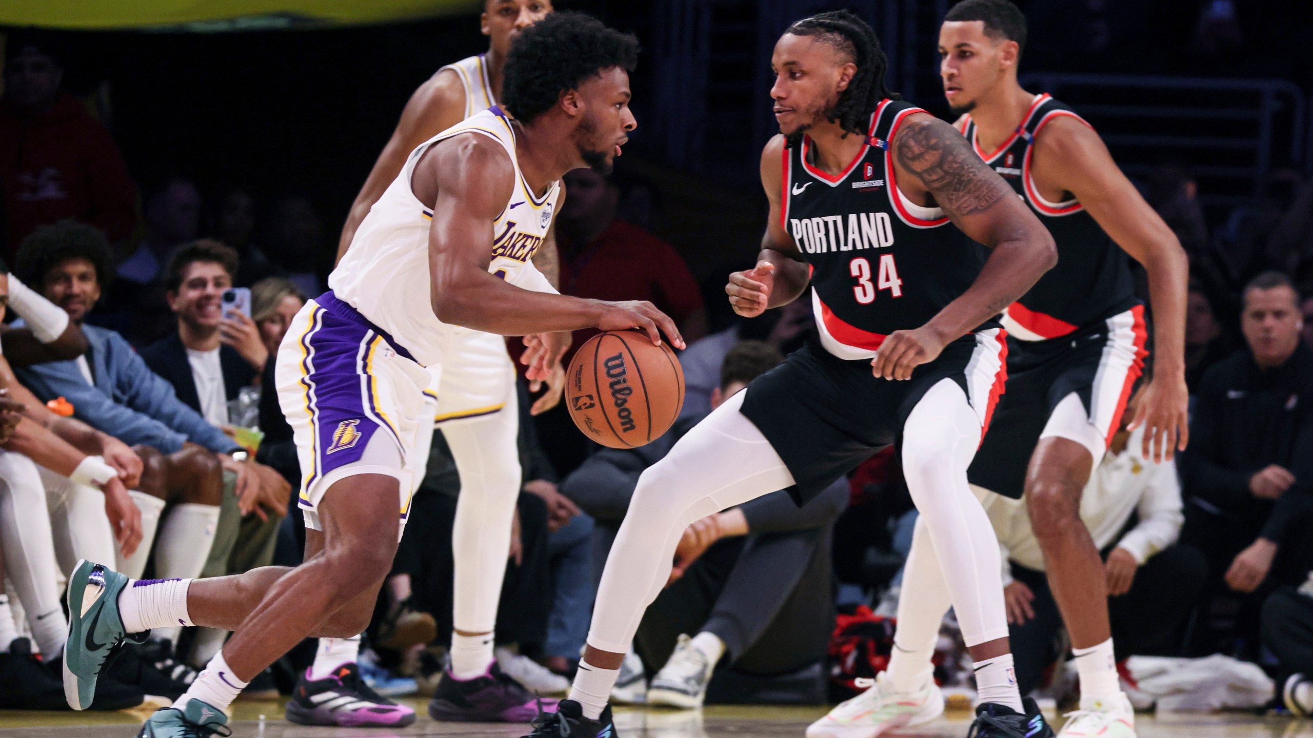 Los Angeles Lakers guard Bronny James, left, dribbles past Portland Trail Blazers' forward Jabari Walker during the second half of an NBA basketball game, Sunday, Dec. 8, 2024, in Los Angeles. (AP Photo/Etienne Laurent)