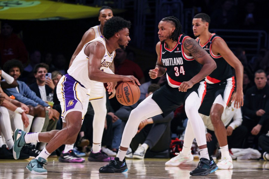 Los Angeles Lakers guard Bronny James, left, dribbles past Portland Trail Blazers' forward Jabari Walker during the second half of an NBA basketball game, Sunday, Dec. 8, 2024, in Los Angeles. (AP Photo/Etienne Laurent)