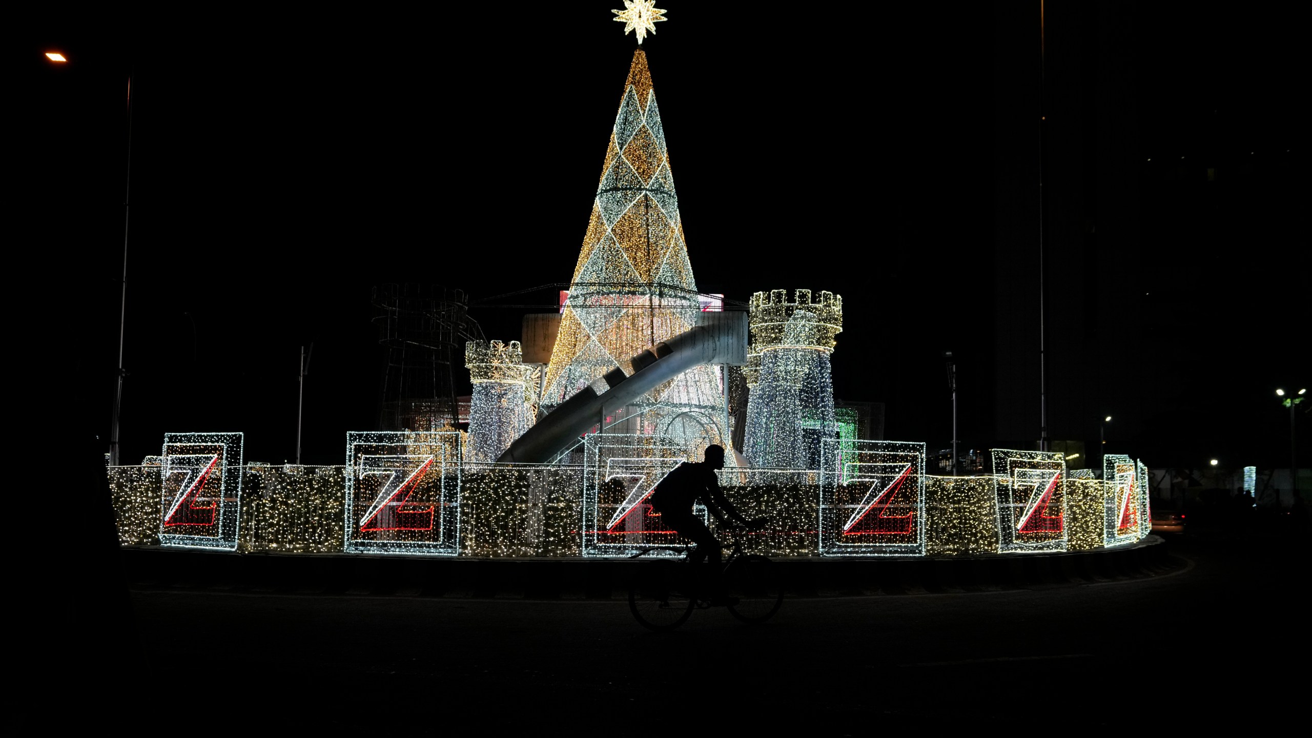 A man rides a bicycle past Christmas decorations on a street in Lagos, Nigeria, Friday, Dec. 20, 2024. (AP Photo/Sunday Alamba)