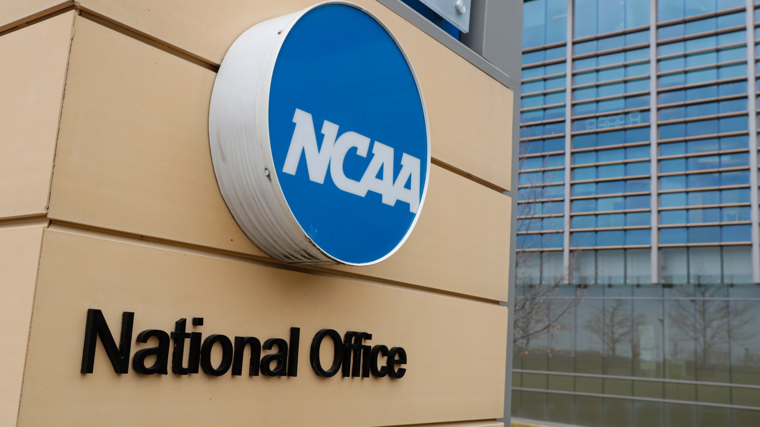 FILE - Signage at the headquarters of the NCAA is viewed in Indianapolis, March 12, 2020. A U.S. appeals court in Philadelphia has ruled that some college athletes may qualify as employees under federal wage-and-hour laws. The court says a test should be developed to differentiate students who play college sports for fun from those whose effort "crosses the legal line into work" that benefits the school. The NCAA had hoped to have the case dismissed.(AP Photo/Michael Conroy, File)