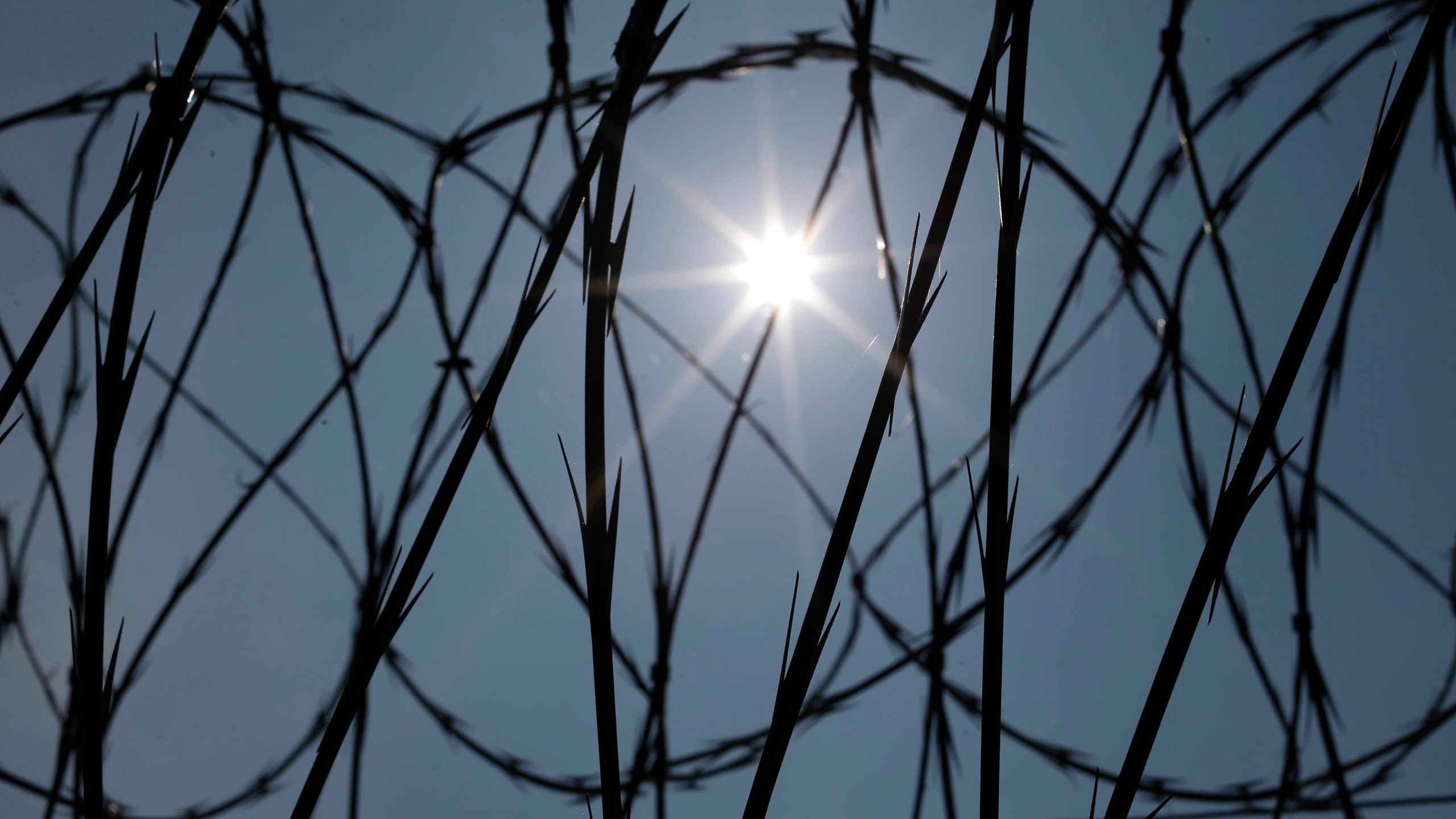 FILE - The sun shines through concertina wire on a fence at the Louisiana State Penitentiary in Angola, La., April 26, 2014. (AP Photo/Gerald Herbert, File)