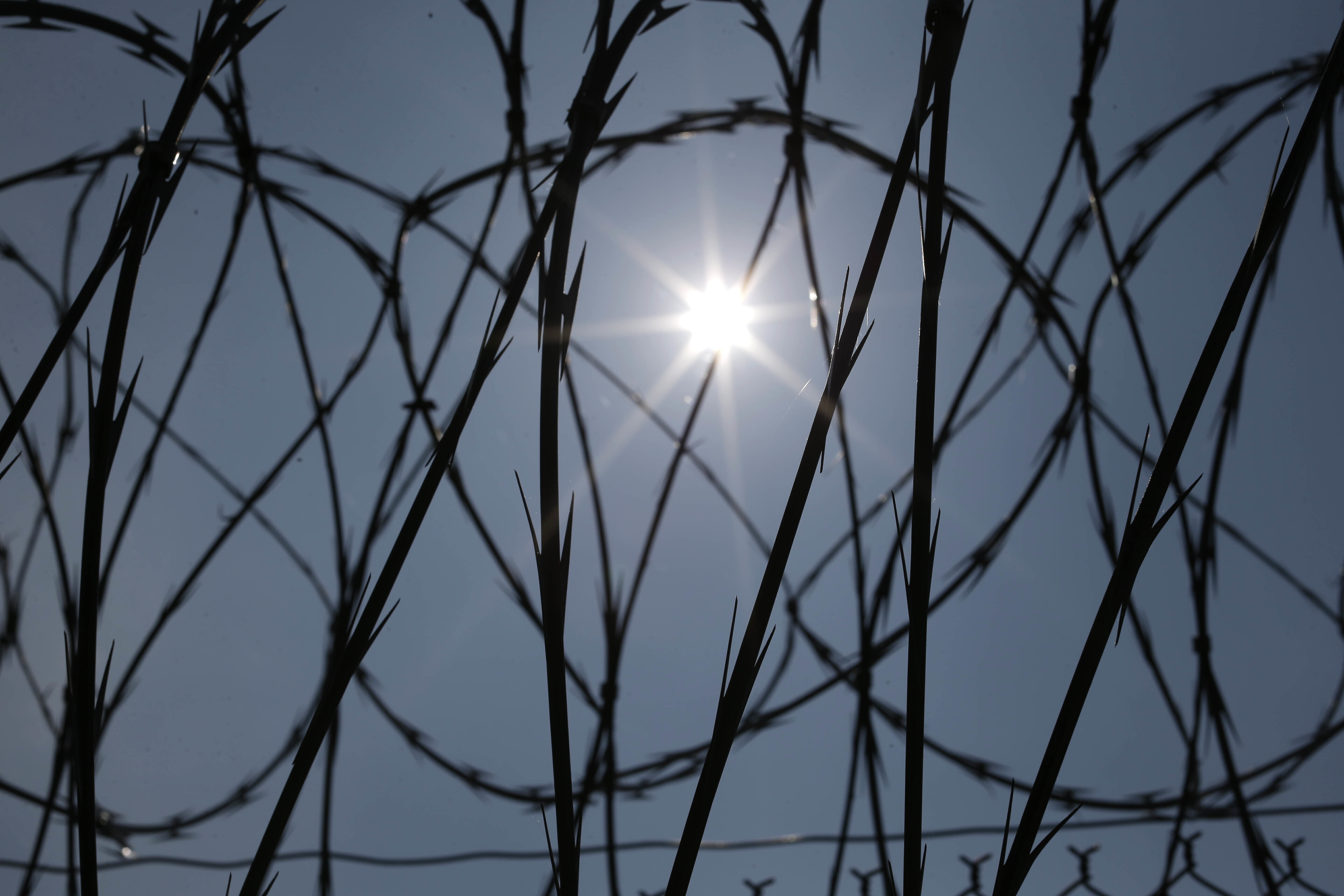 FILE - The sun shines through concertina wire on a fence at the Louisiana State Penitentiary in Angola, La., April 26, 2014. (AP Photo/Gerald Herbert, File)