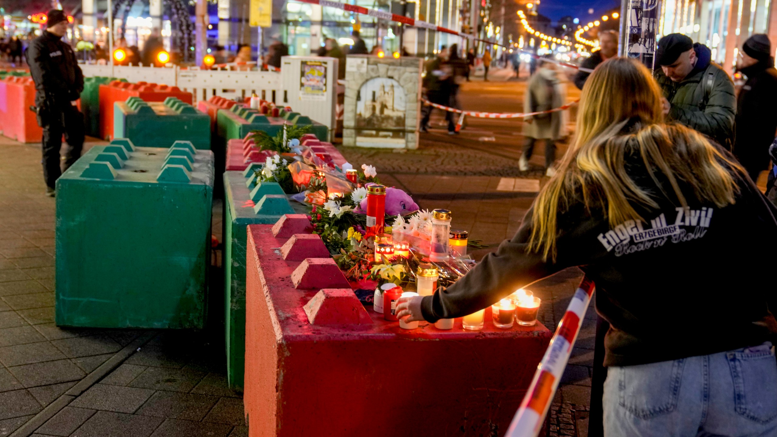 People lay flowers and light candles on concrete blocks that protect the Christmas market in Magdeburg, Germany, Saturday, Dec. 21, 2024, where a car drove into a crowd on Friday evening. (AP Photo/Michael Probst)