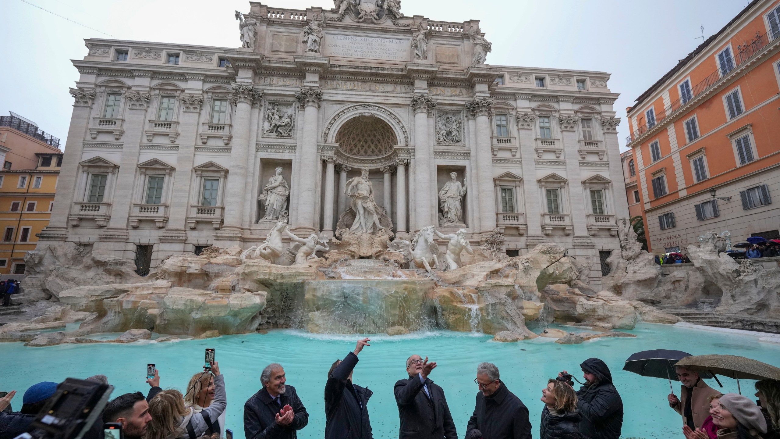 Rome's mayor Roberto Gualtieri, center, tosses a coin into the 18th century Trevi Fountain, one of Rome's most iconic landmarks, as it reopens to the public after undergoing maintenance, just on time for the start of the Jubilee Year, an event expected to draw millions of visitors to the Eternal City, in Rome, Sunday, Dec. 22, 2024. (AP Photo/Andrew Medichini)