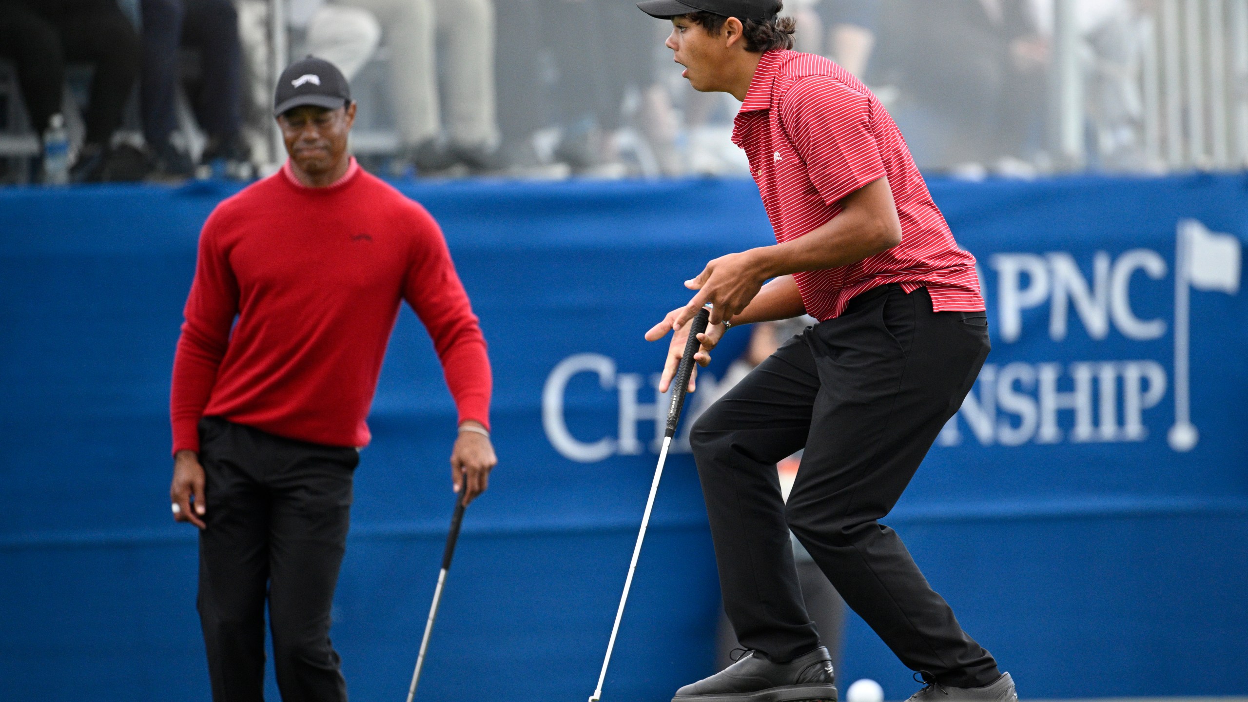 Tiger Woods, left, and Charlie Woods react after missing a putt during a playoff hole on the 18th green to win the PNC Championship golf tournament, Sunday, Dec. 22, 2024, in Orlando, Fla. (AP Photo/Phelan M. Ebenhack)