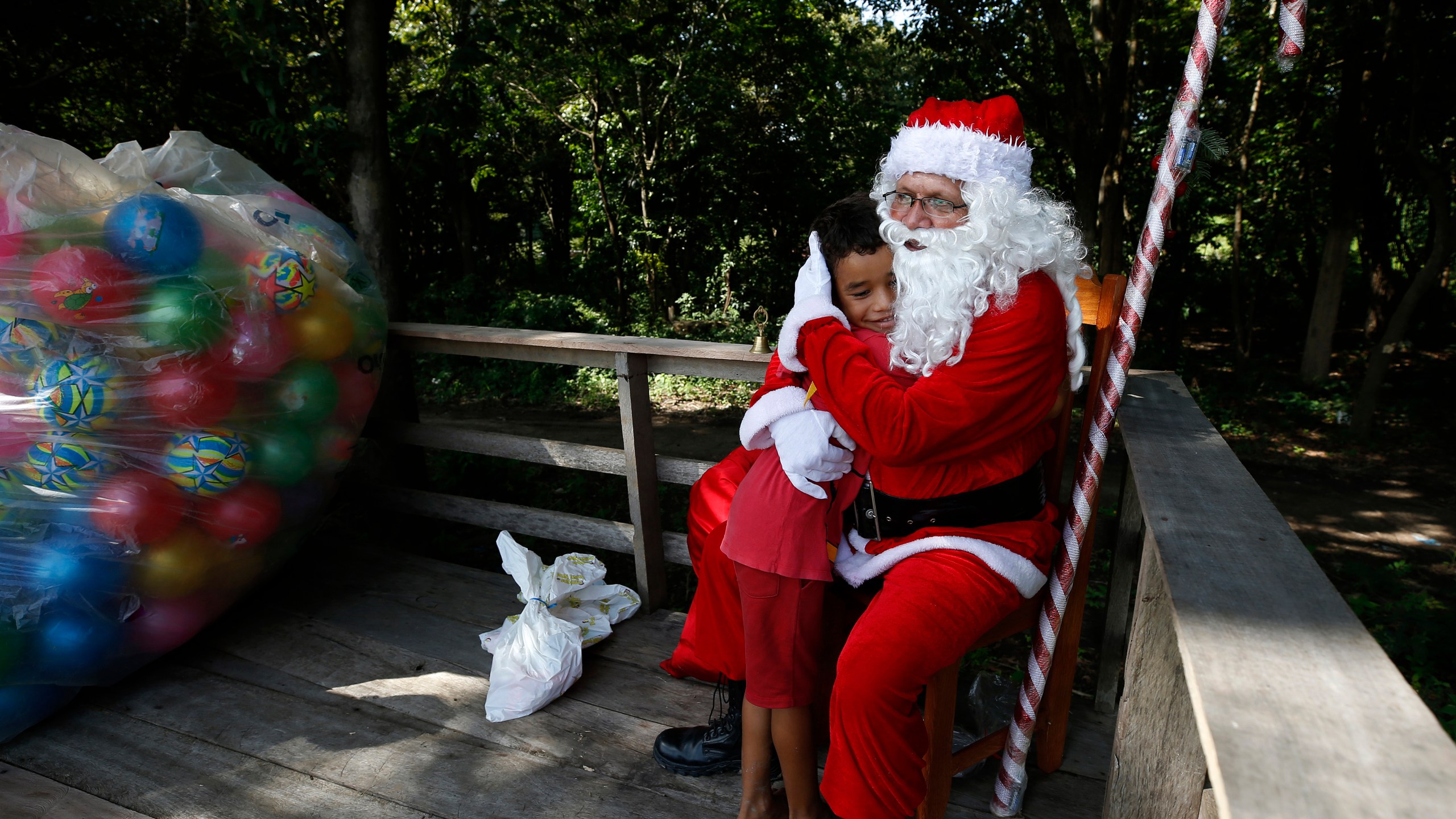 Jorge Barroso, dressed as Santa Claus, is embraced by a young resident after arriving on a boat to distribute Christmas gifts to children who live in the riverside communities of the Amazon, in Iranduba, Brazil, Saturday, Dec. 21, 2024. (AP Photo/Edmar Barros)