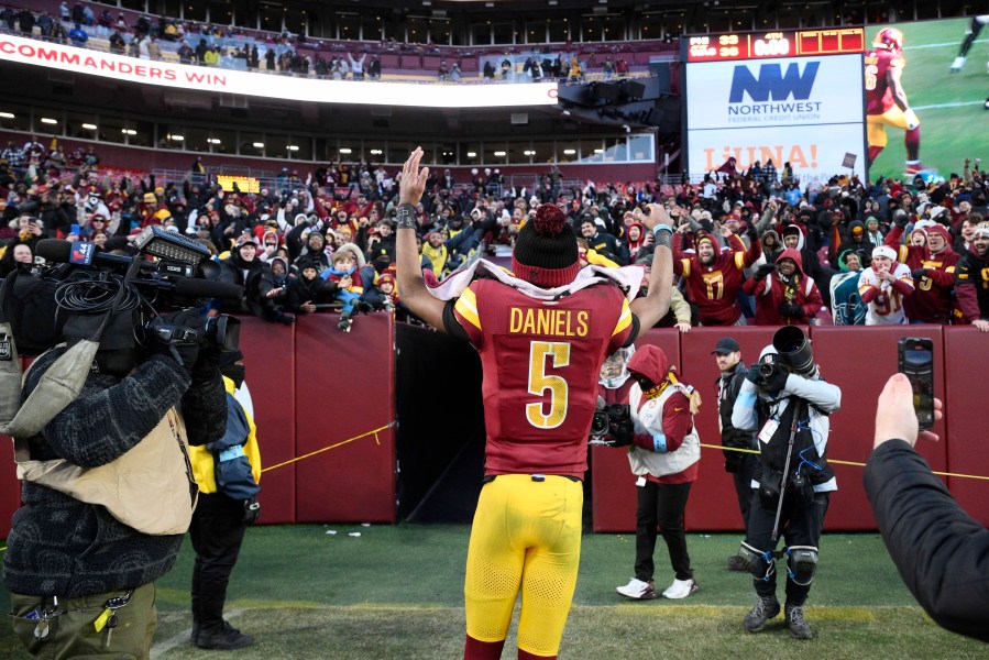 Washington Commanders quarterback Jayden Daniels (5) acknowledges fans as he heads off the field at the end of an NFL football game against the Philadelphia Eagles, Sunday, Dec. 22, 2024, in Landover, Md. (AP Photo/Nick Wass)