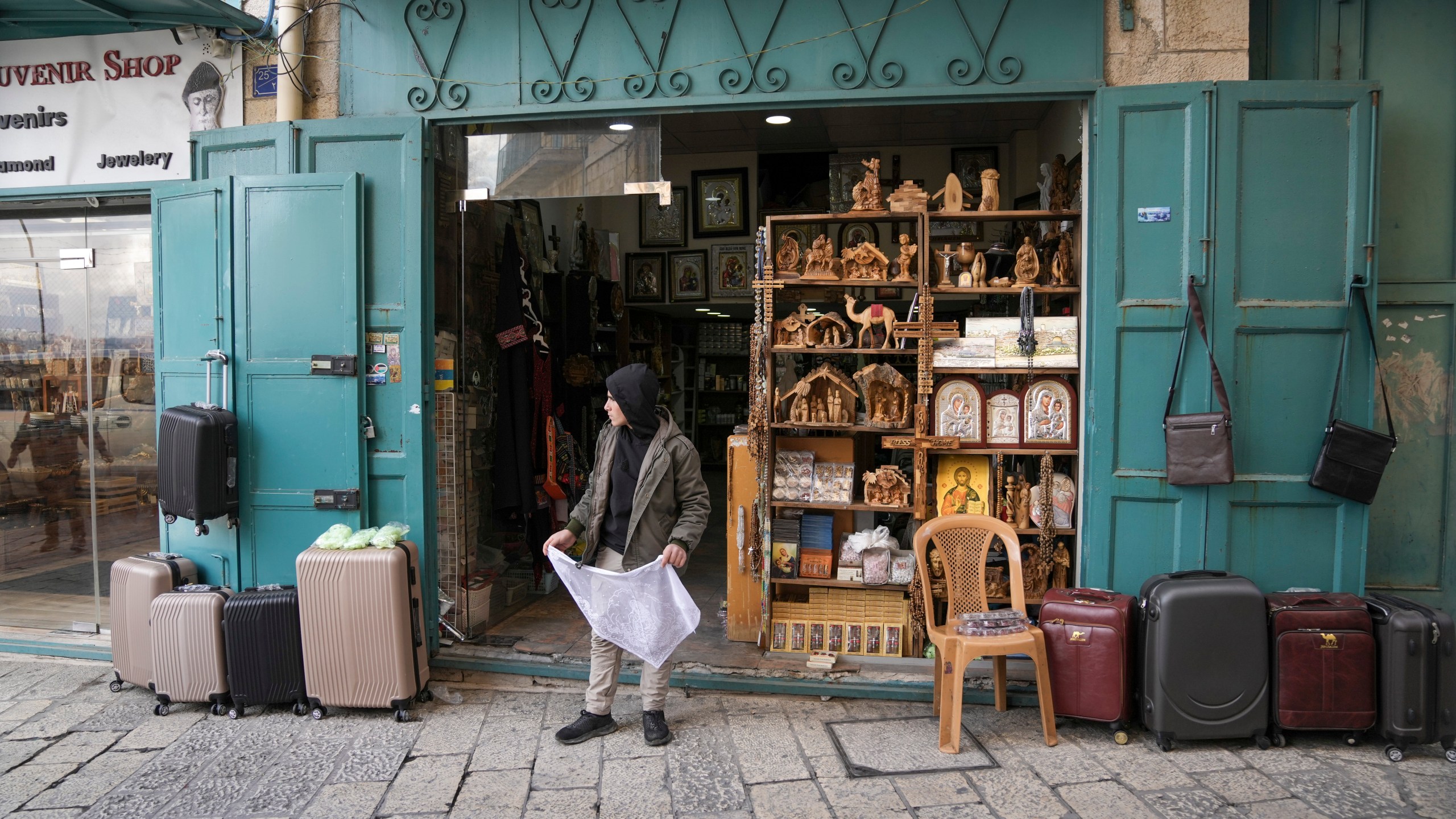 A boy waits outside a souvenir shop near the Church of the Nativity, where Christians believe Jesus Christ was born, ahead of Christmas in the West Bank city of Bethlehem, Saturday Dec. 21, 2024. (AP Photo/Mahmoud Illean)