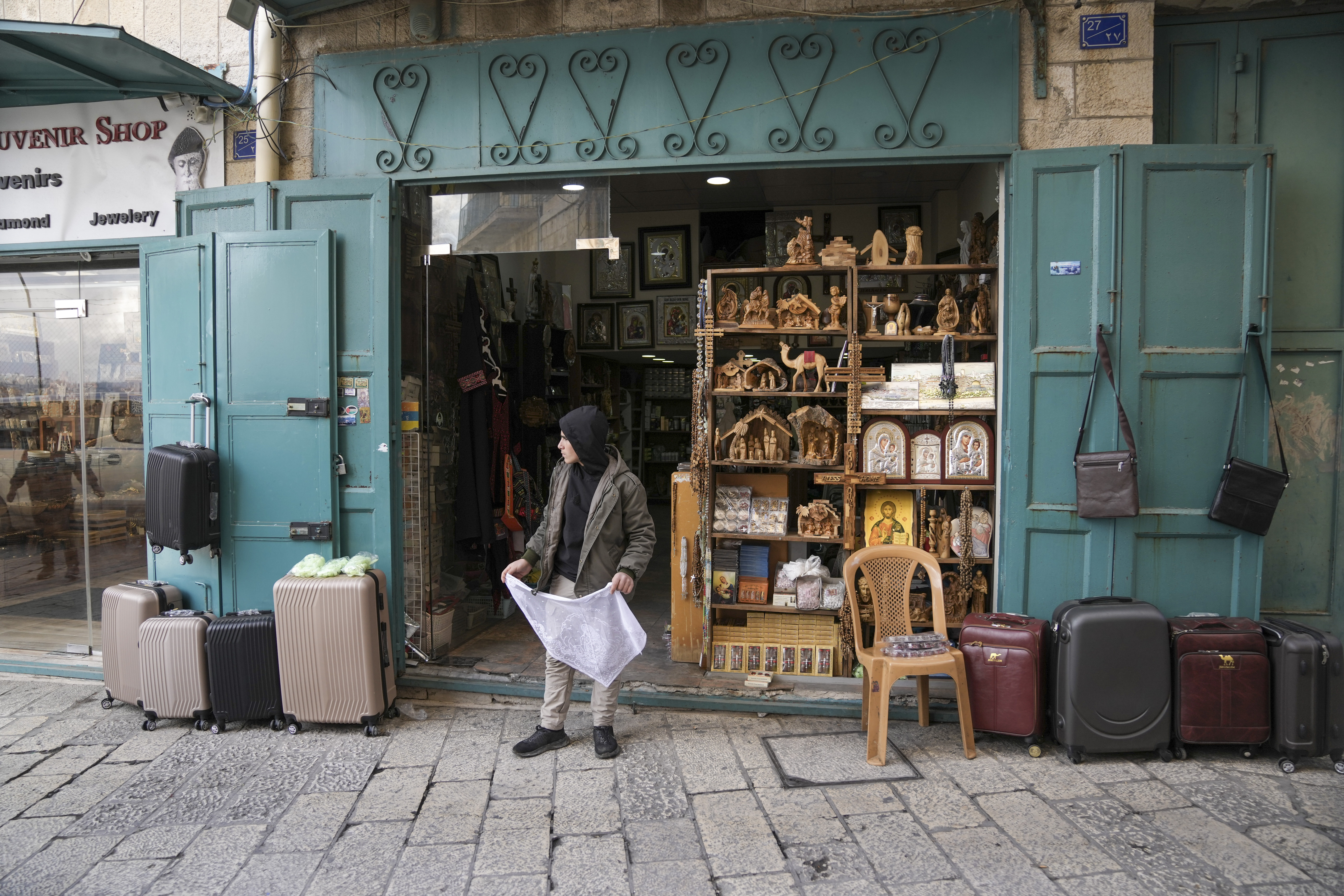 A boy waits outside a souvenir shop near the Church of the Nativity, where Christians believe Jesus Christ was born, ahead of Christmas in the West Bank city of Bethlehem, Saturday Dec. 21, 2024. (AP Photo/Mahmoud Illean)