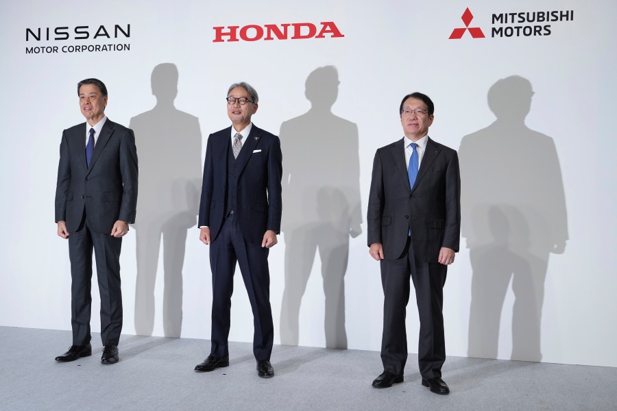 Nissan Chief Executive Makoto Uchida, left, Honda Chief Executive Toshihiro Mibe, center, and Takao Kato, CEO of Mitsubishi Motors, right, pose for photographers during a joint news conference in Tokyo, Japan, Monday, Dec. 23, 2024. (AP Photo/Eugene Hoshiko)