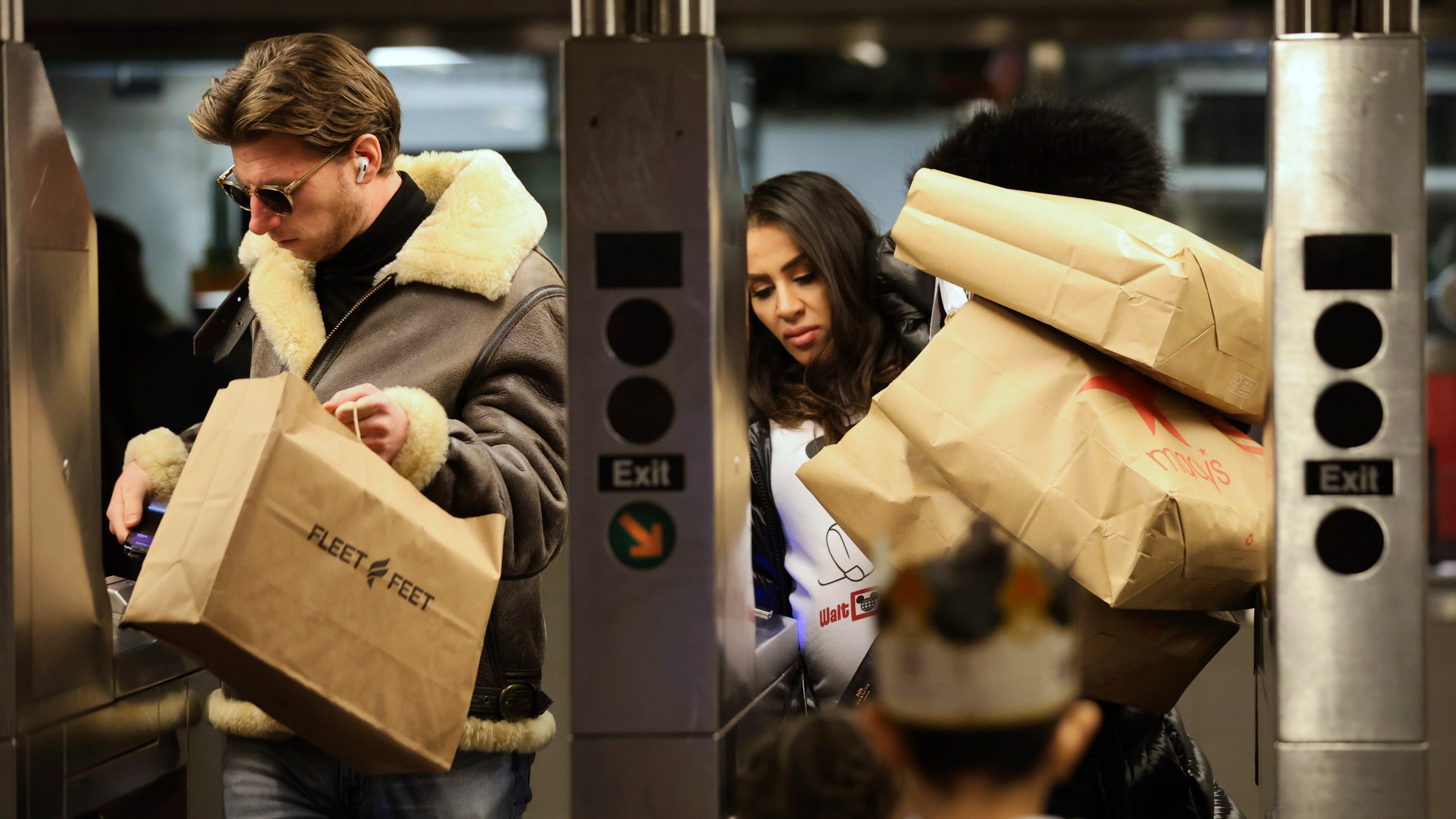 FILE - Shoppers manage their bags as they enter a subway turnstile, Nov. 29, 2024, in New York. (AP Photo/Heather Khalifa, File)