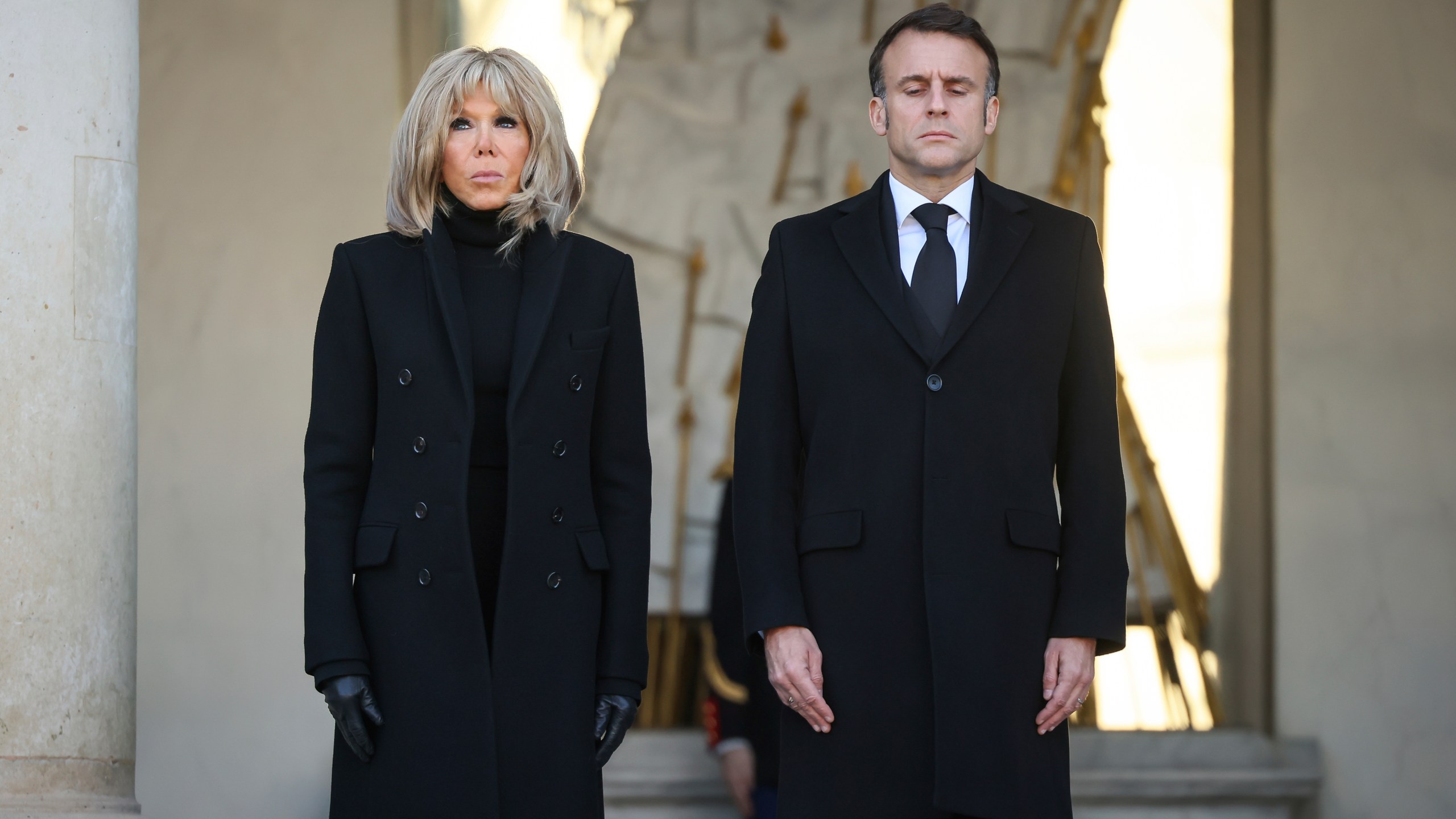 French President Emmanuel Macron and his wife Brigitte Macron stand for a minute of silence Monday, Dec. 23, 2024 at the Elysee Palace, in Paris, after Macron declared a day of national mourning for the lives lost when Cyclone Chido ripped through the Indian Ocean territory of Mayotte. (AP Photo/Thomas Padilla, Pool)