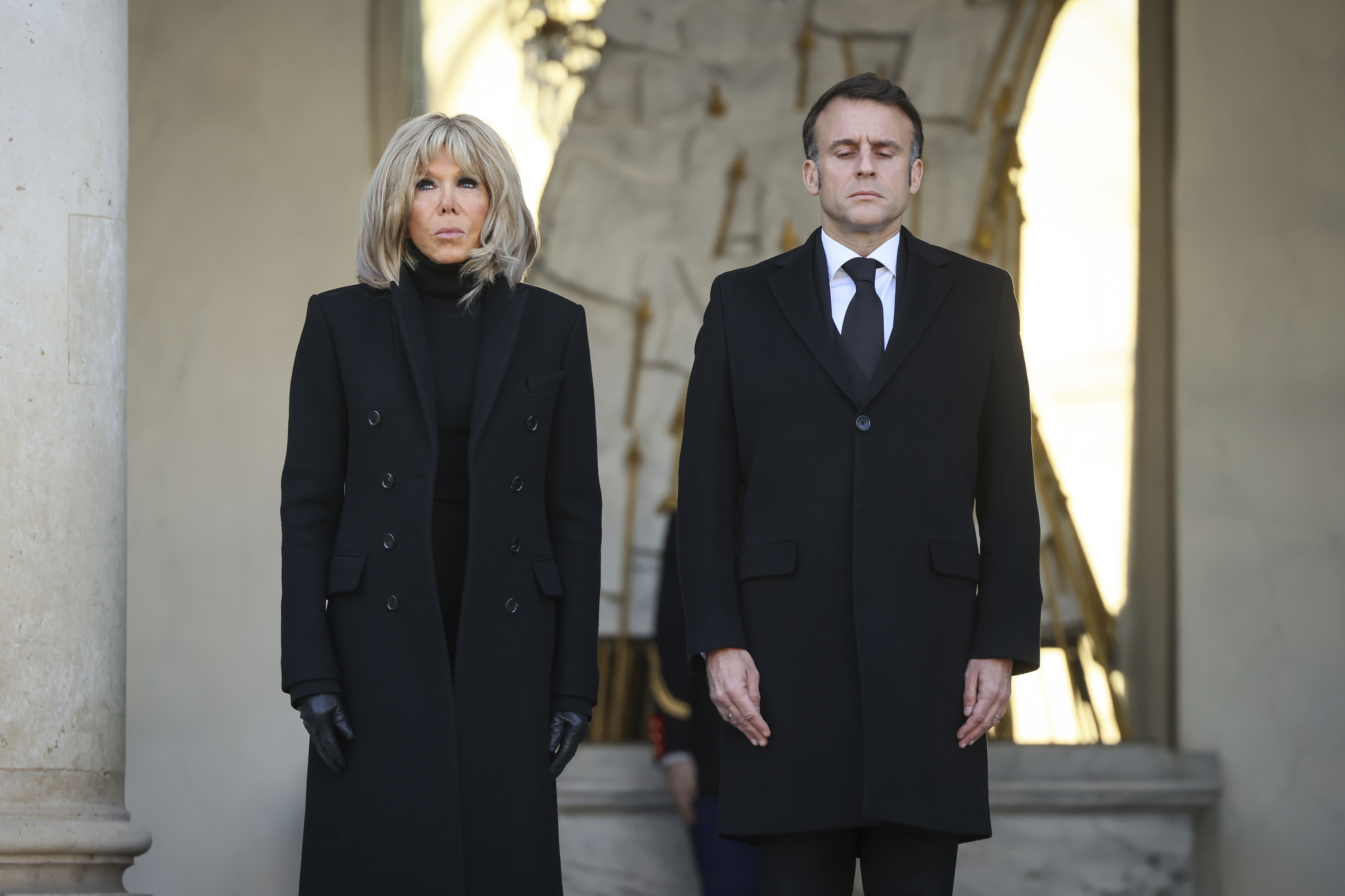 French President Emmanuel Macron and his wife Brigitte Macron stand for a minute of silence Monday, Dec. 23, 2024 at the Elysee Palace, in Paris, after Macron declared a day of national mourning for the lives lost when Cyclone Chido ripped through the Indian Ocean territory of Mayotte. (AP Photo/Thomas Padilla, Pool)