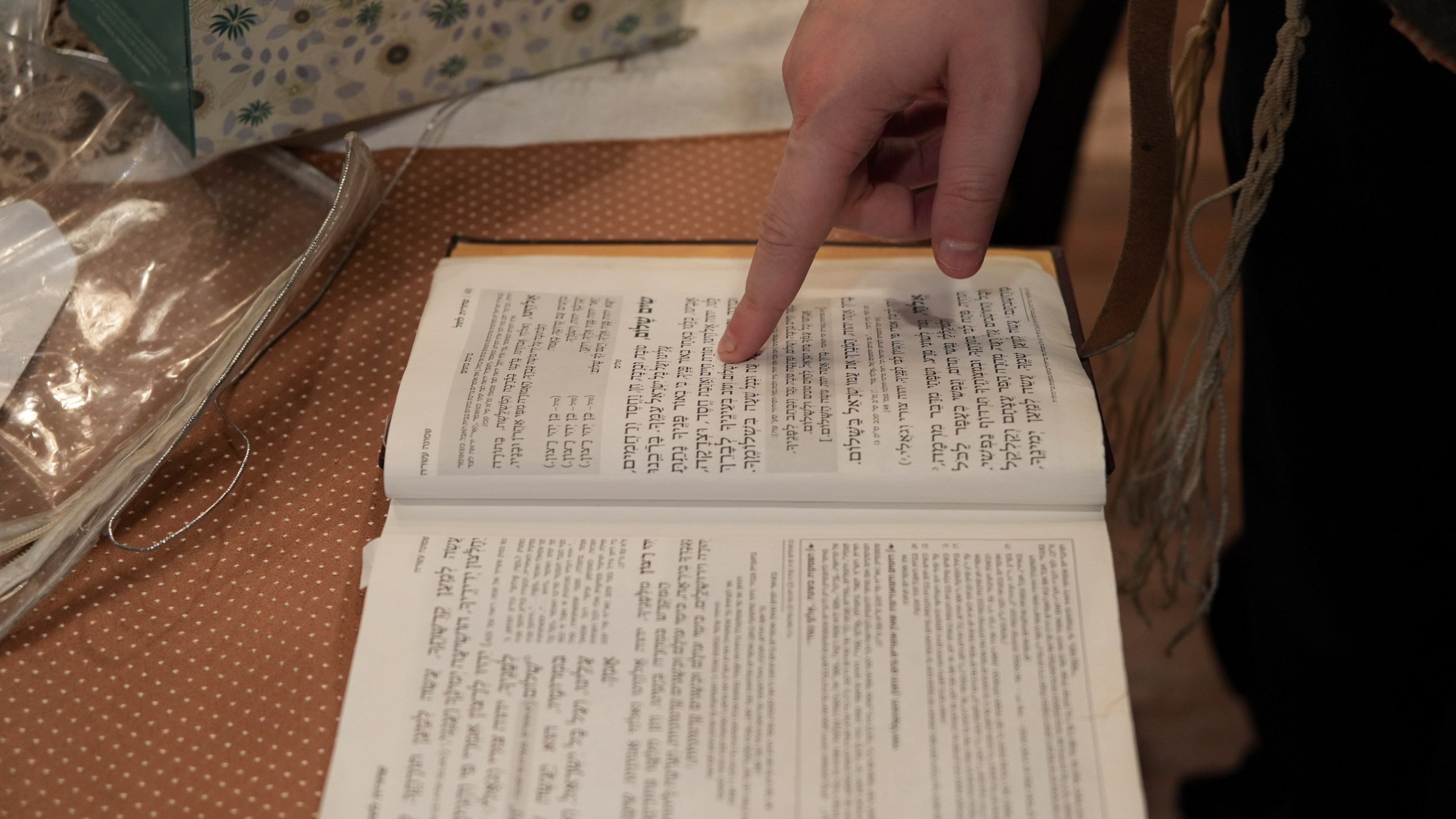 Dov Marcus points to prayers as he reads from the Jewish prayer book in Teaneck, N.J., on Friday, Dec. 20, 2024. (AP Photo/Luis Andres Henao)