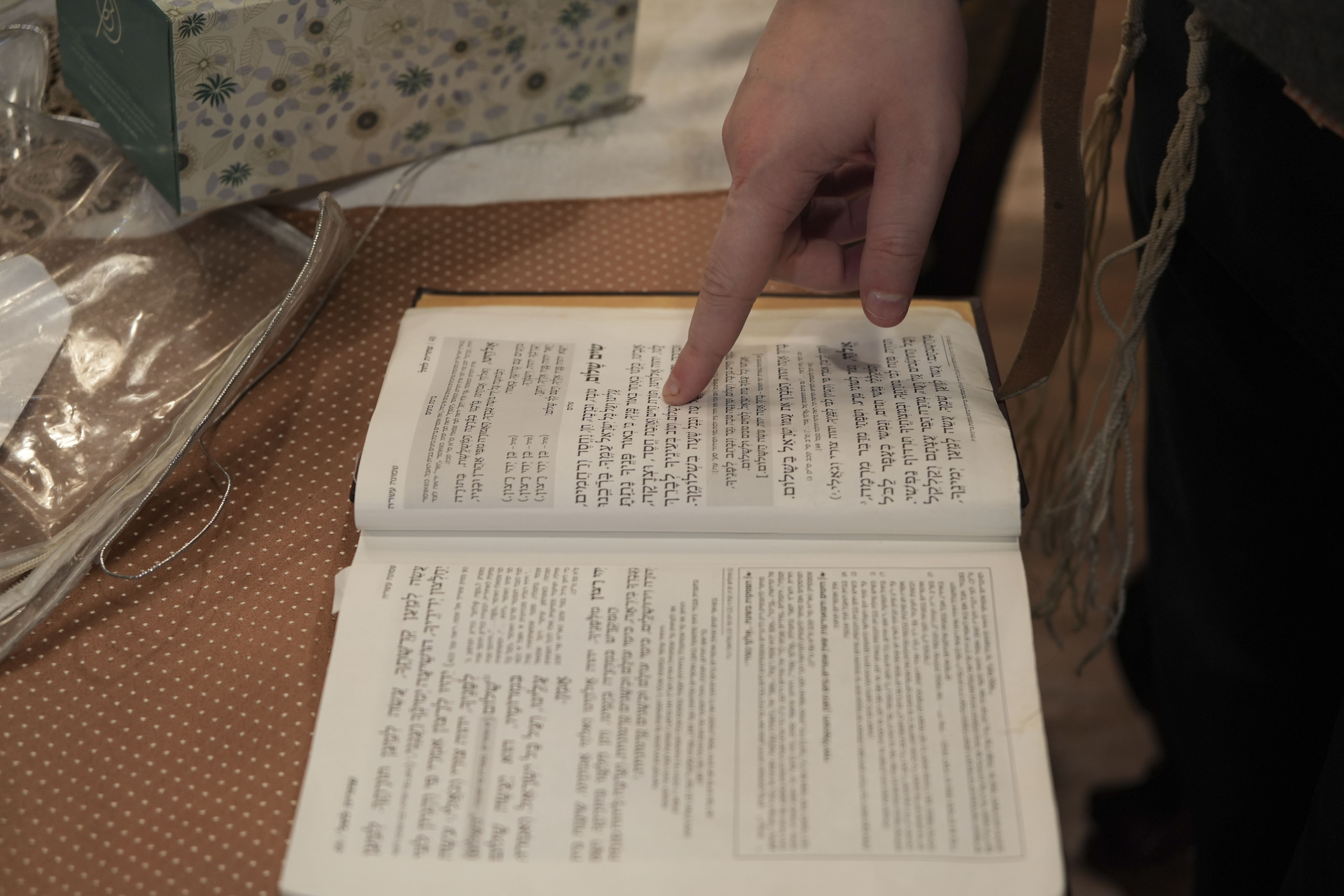 Dov Marcus points to prayers as he reads from the Jewish prayer book in Teaneck, N.J., on Friday, Dec. 20, 2024. (AP Photo/Luis Andres Henao)