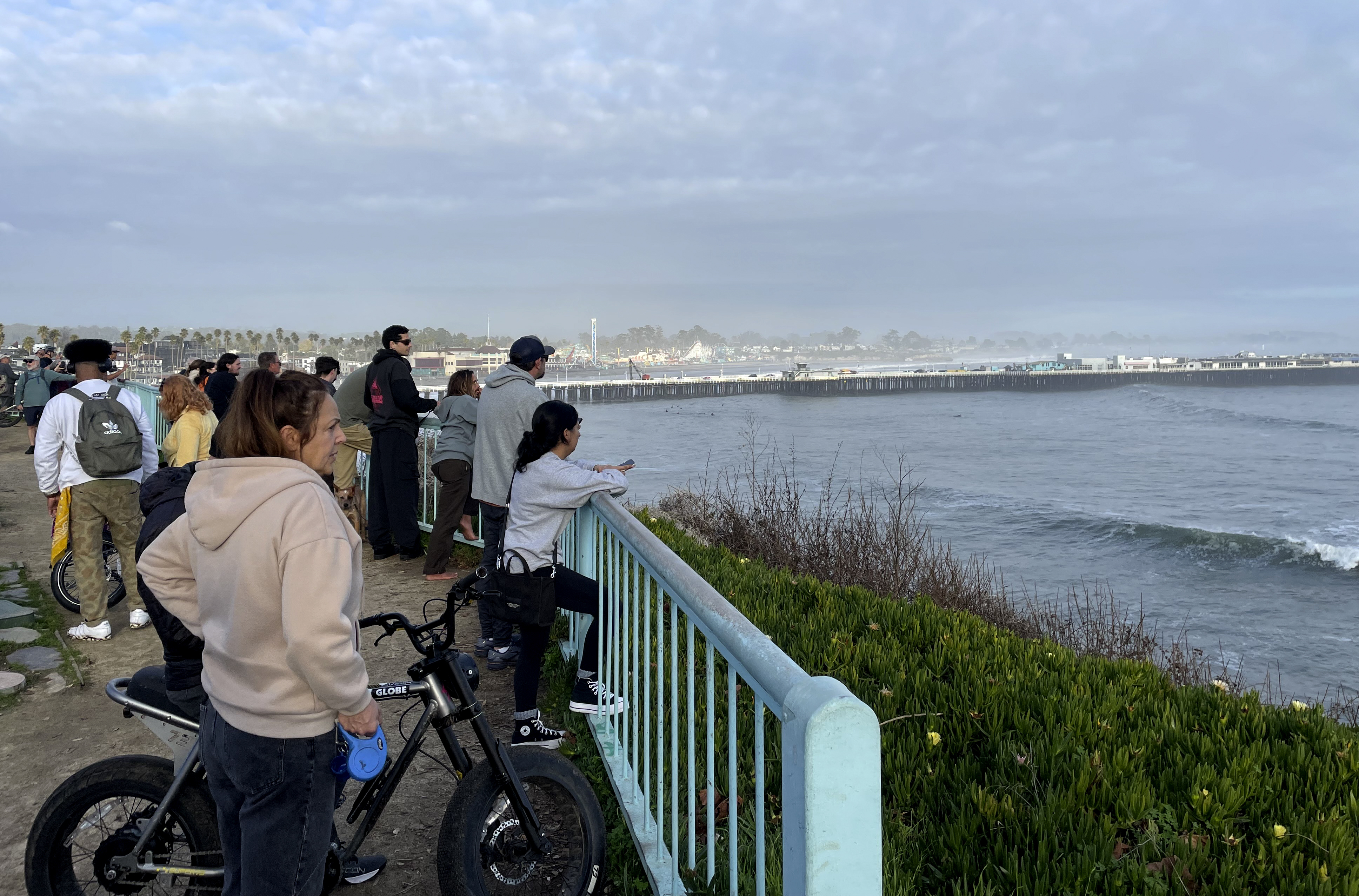 Spectators look out at a closed Santa Cruz wharf after the pier partially collapsed and fell into the ocean on Monday, Dec. 23, 2024, in Santa Cruz, Calif. (AP Photo/Martha Mendoza)